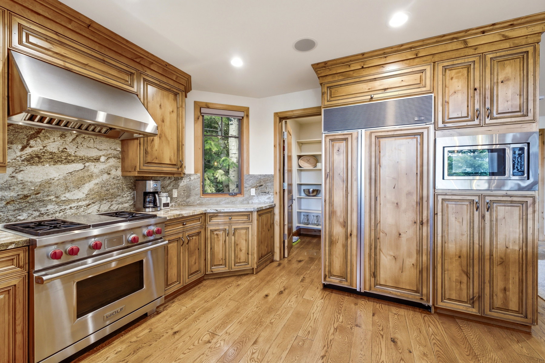 Kitchen featuring knotty wood cabinetry, granite countertops, stainless steel appliances, and wood-finish flooring