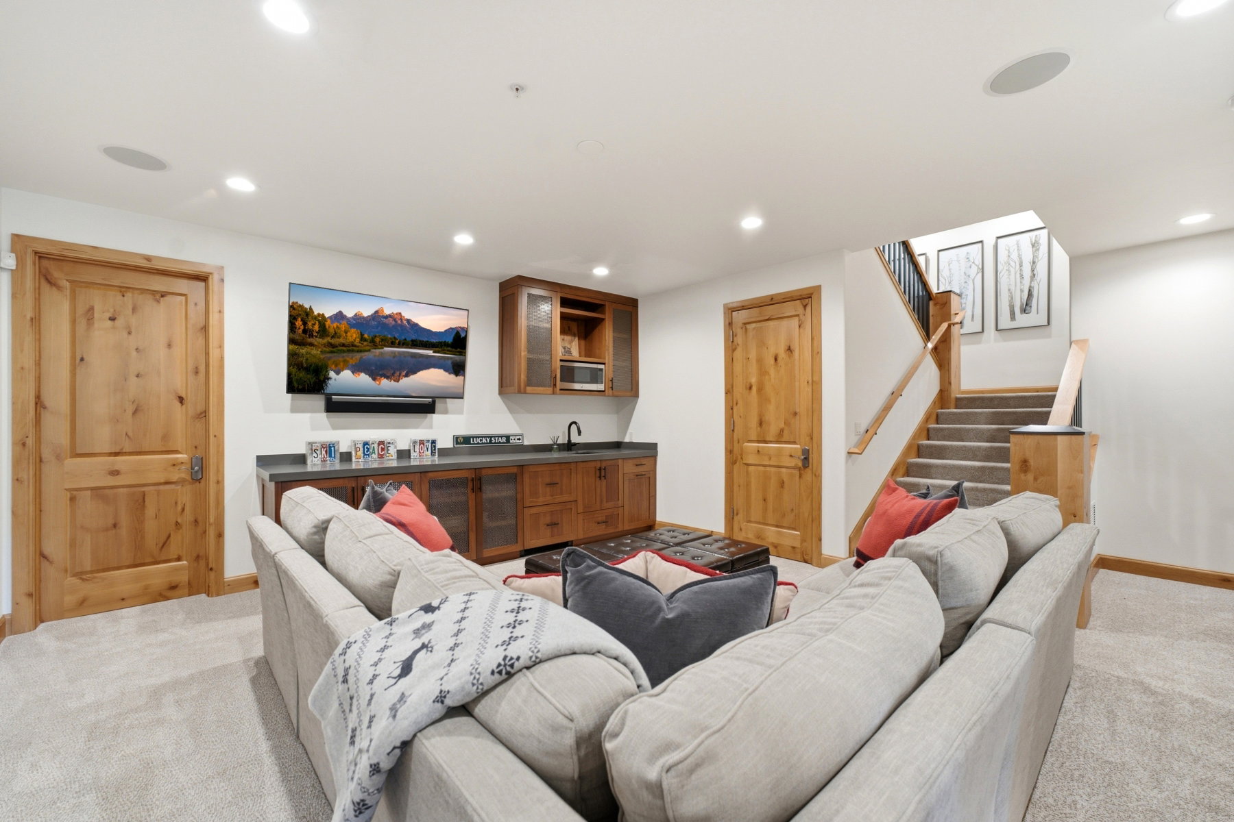 Entertainment area featuring a built-in wet bar with wood cabinetry and dark stone countertop, recessed lighting, and light-toned carpeting