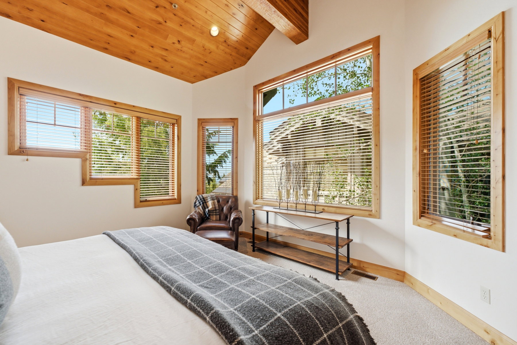 Bedroom featuring a vaulted wood-paneled ceiling with exposed beams, multiple windows with wood trim, and carpet flooring