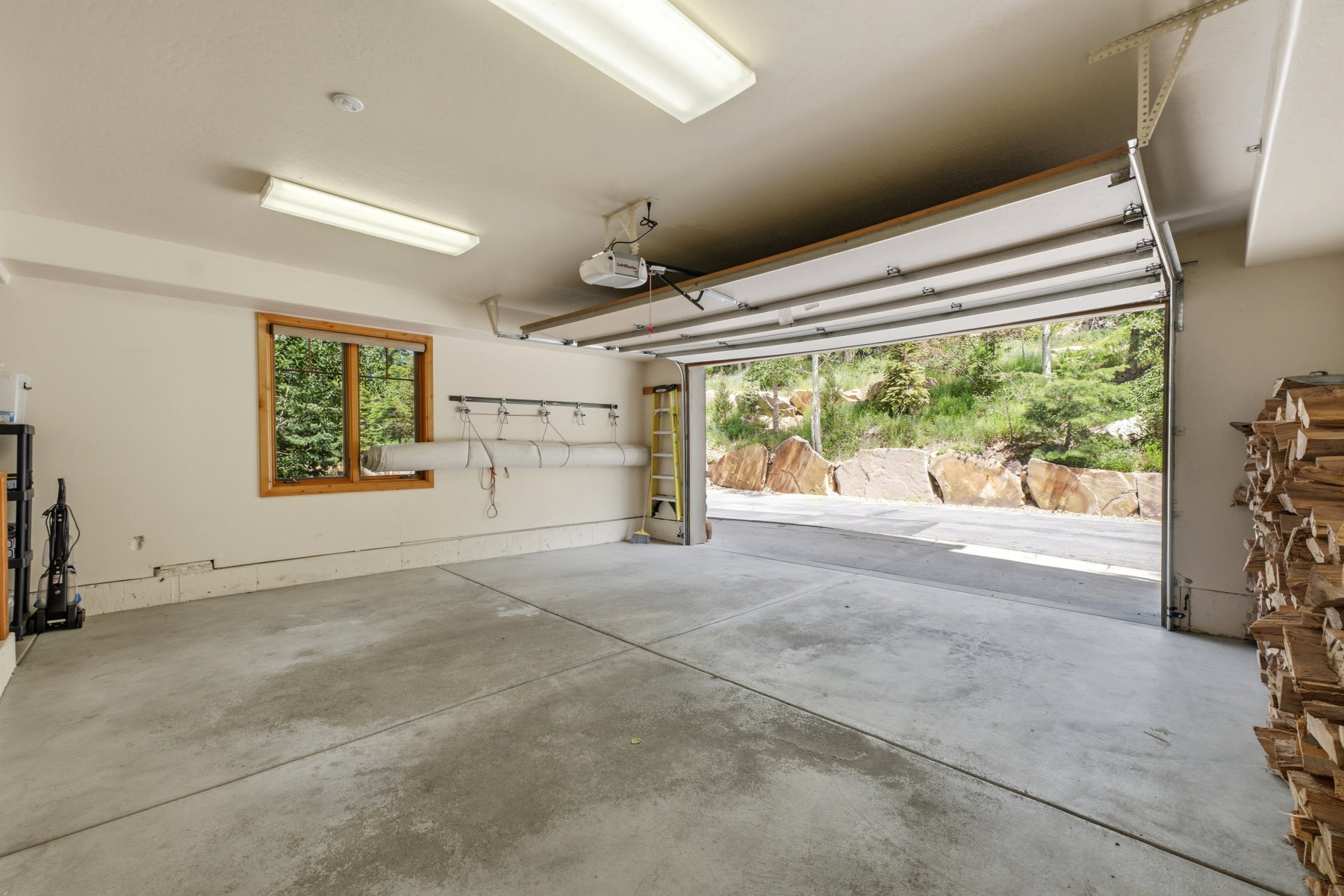 Spacious garage featuring a concrete floor, overhead fluorescent lighting, and a wide wooden-framed window