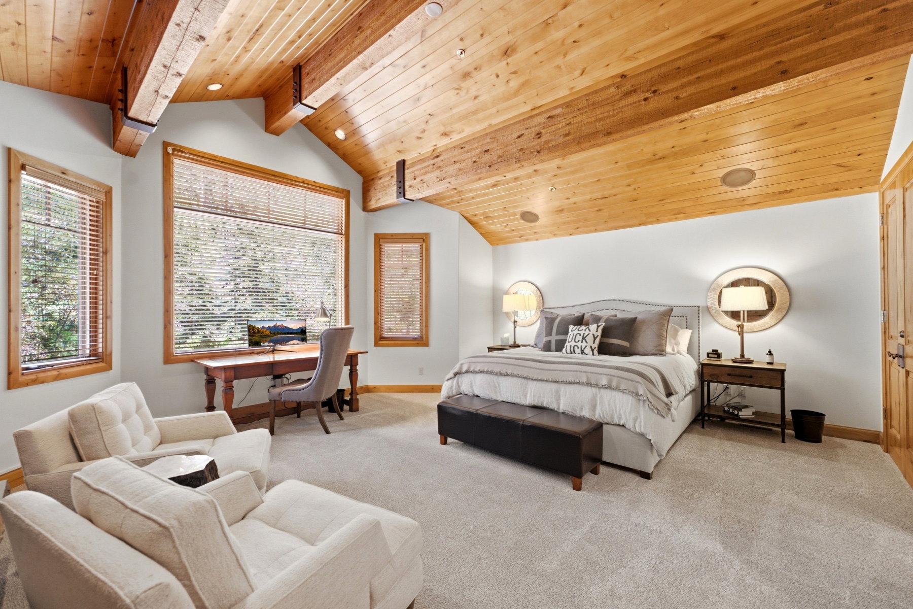 Spacious interior featuring a vaulted wood-plank ceiling with exposed beams, light-colored walls, and expansive windows