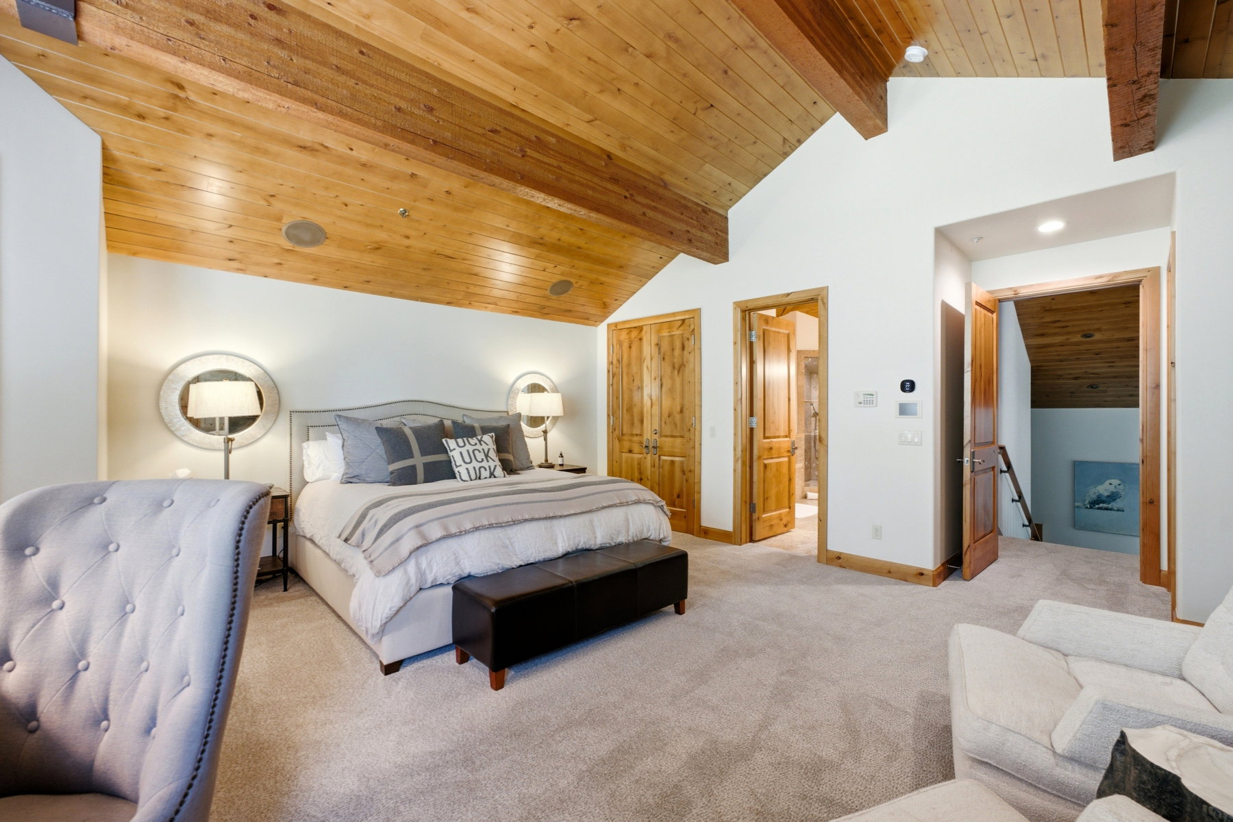 Vaulted wood-paneled ceiling with exposed beams, light-toned carpeting, wood-finish doors, and recessed lighting