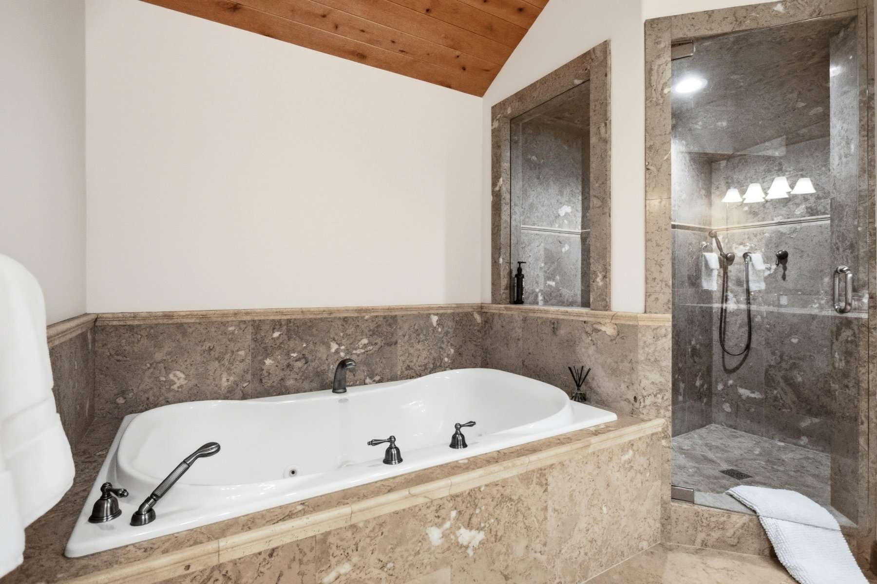 Soaking tub with dark bronze fixtures, set within a natural stone surround