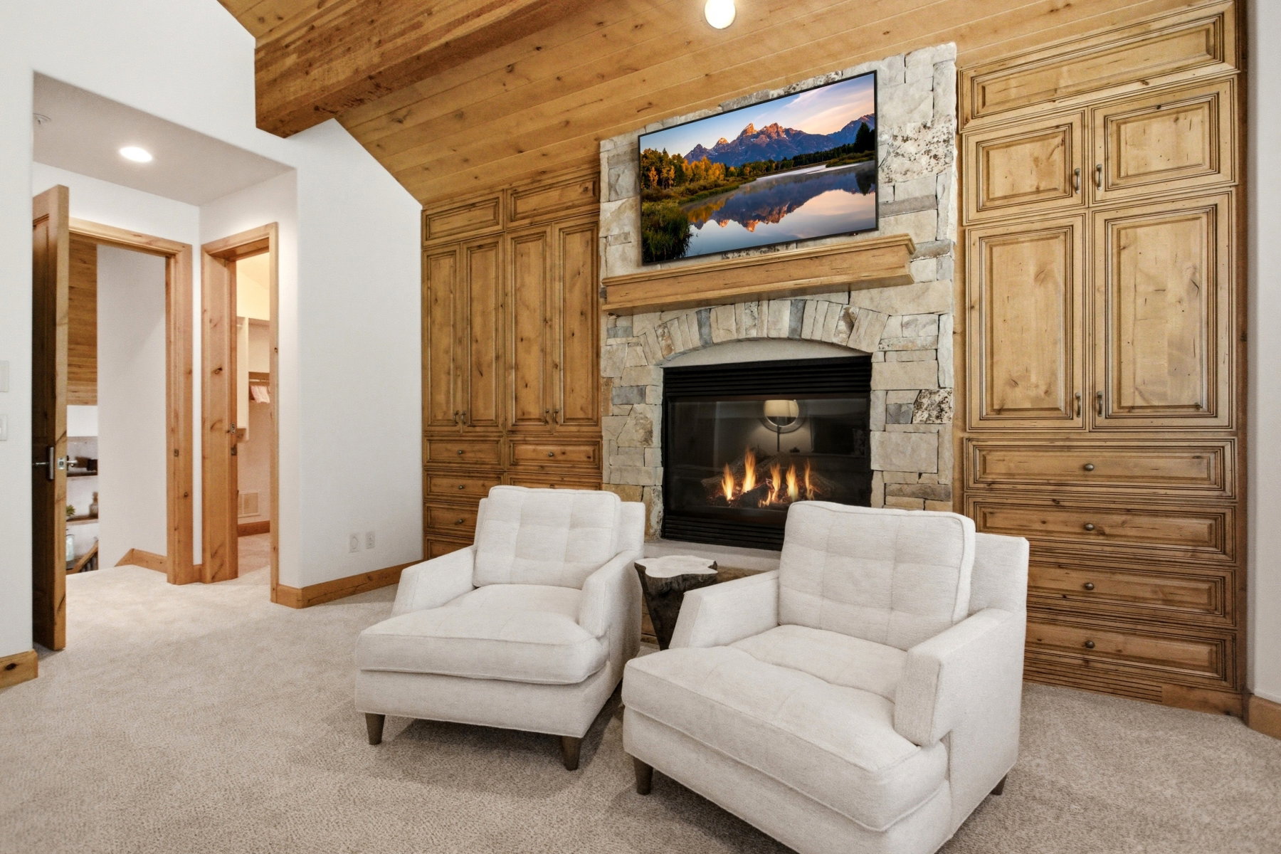 Stone-clad fireplace with a built-in media center, wood-finish ceiling, and integrated lighting