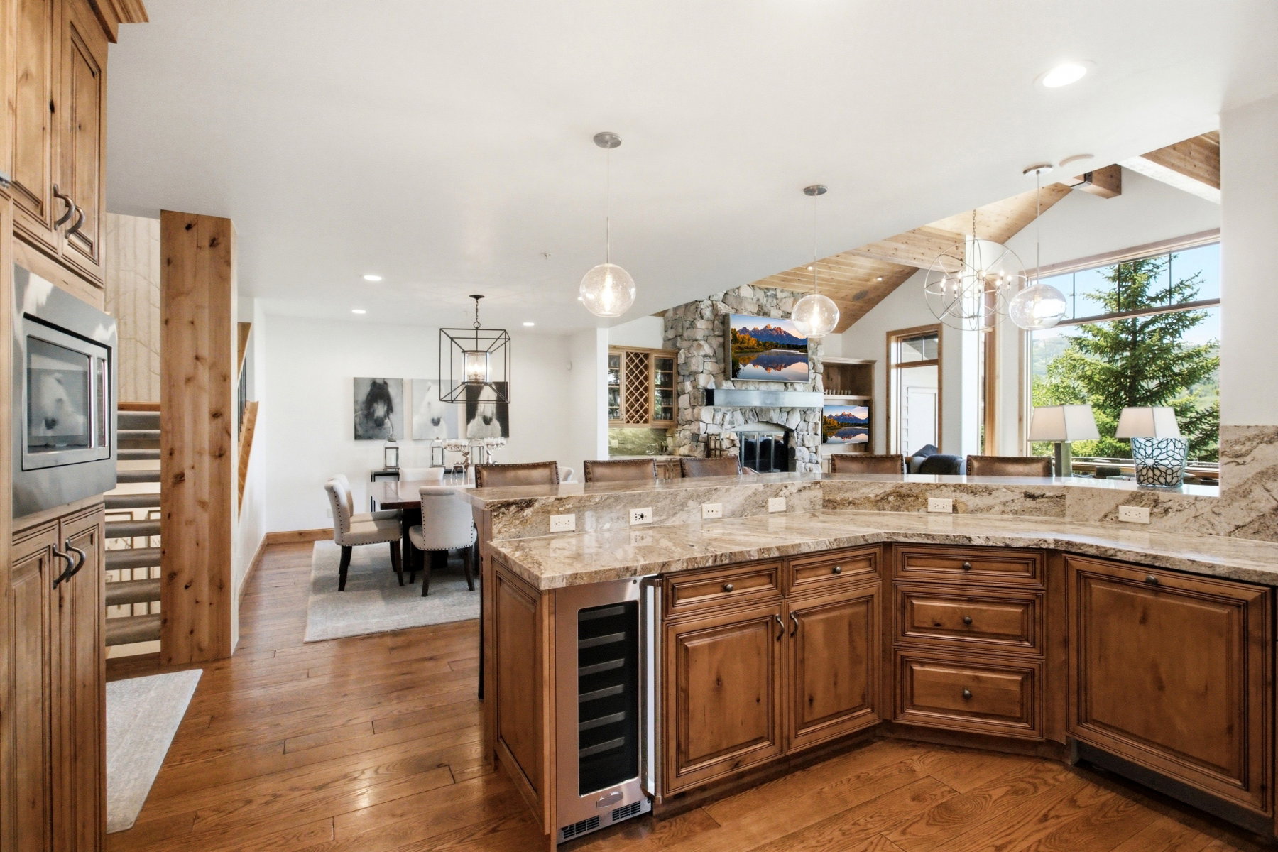 Kitchen featuring wood cabinetry, stone countertops, a built-in wine cooler, and hardwood flooring