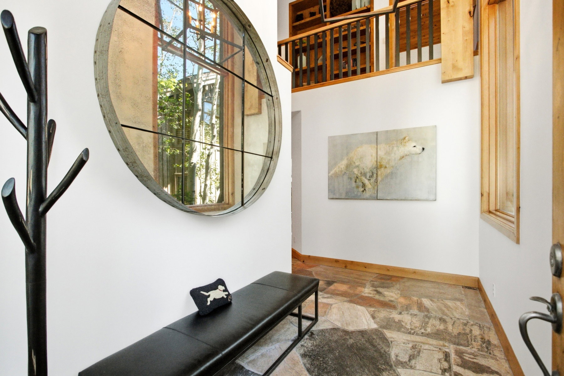 Foyer with multi-toned stone flooring, white walls, and a round window with dark grid details