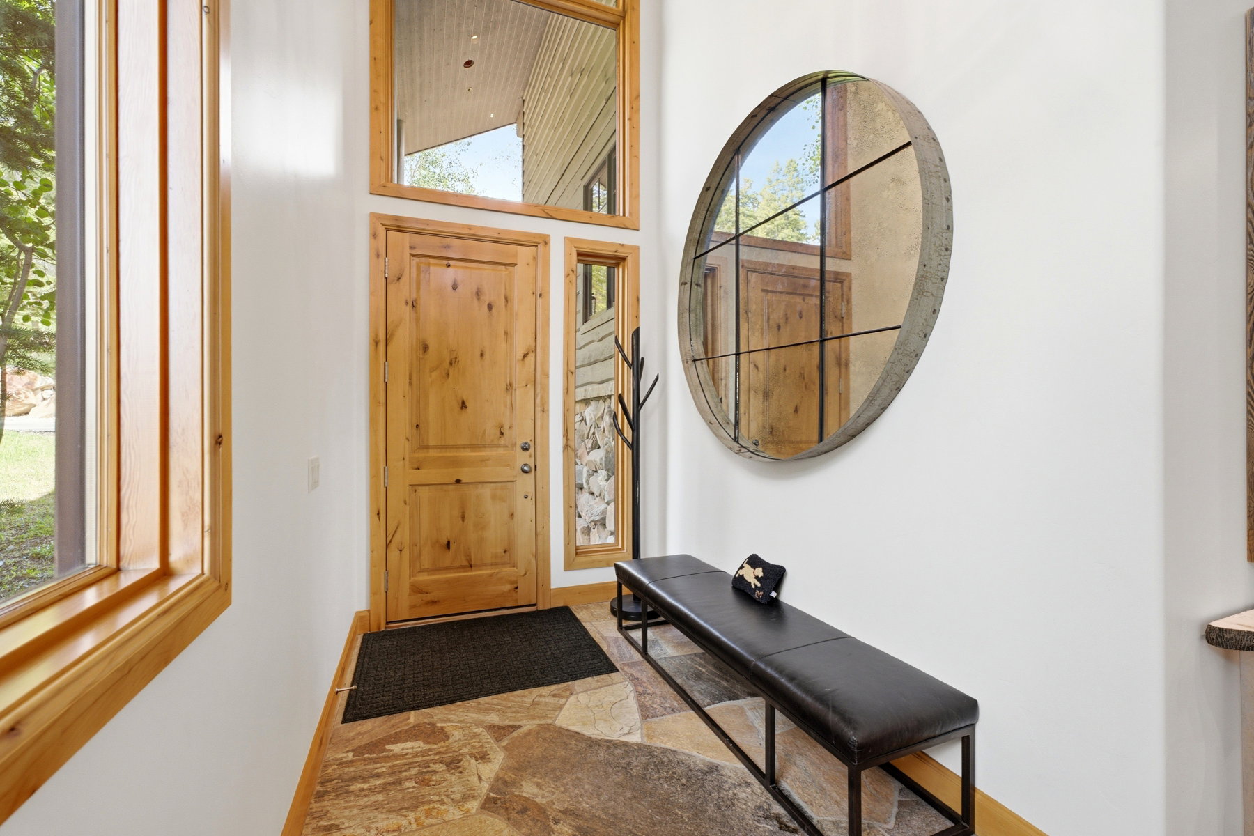 Entryway featuring natural wood door with sidelight windows, a large fixed pane window, and flagstone flooring