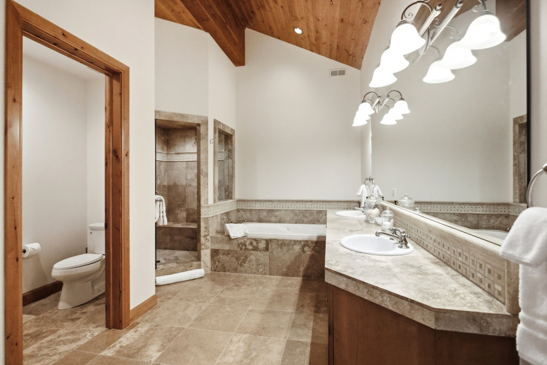 Spacious bathroom featuring a double vanity with integrated sinks, an oversized soaking tub, and a separate walk-in shower with a built-in bench