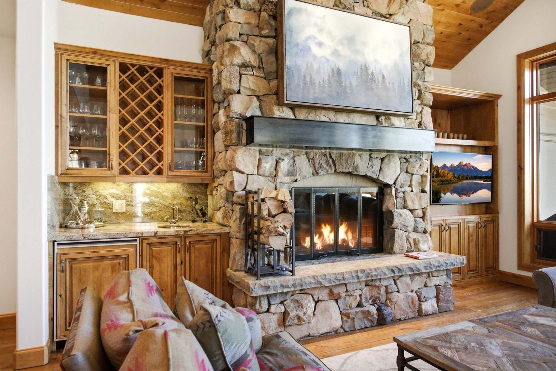 Stone-clad fireplace with a raised hearth, wood-finish flooring, and a vaulted wood-paneled ceiling