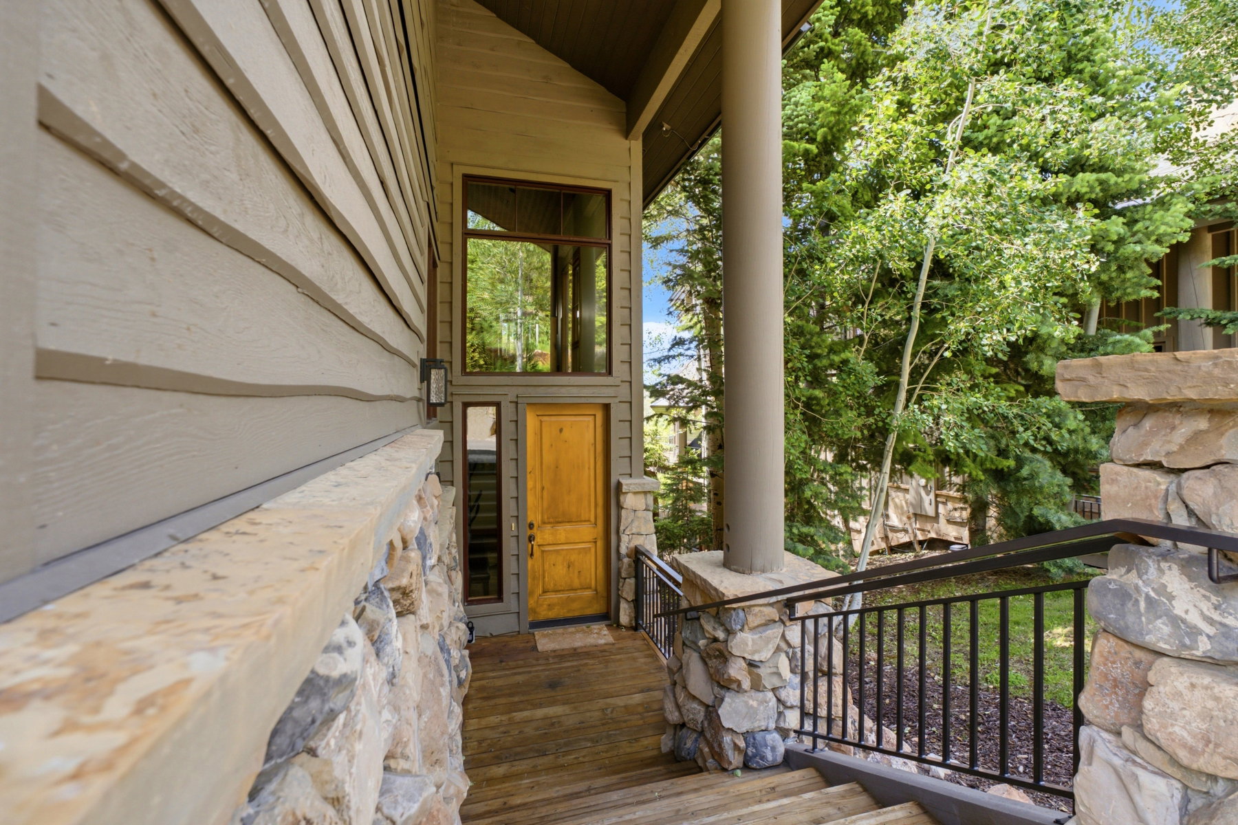 Stone and wood-finish siding exterior featuring a prominent wood entry door