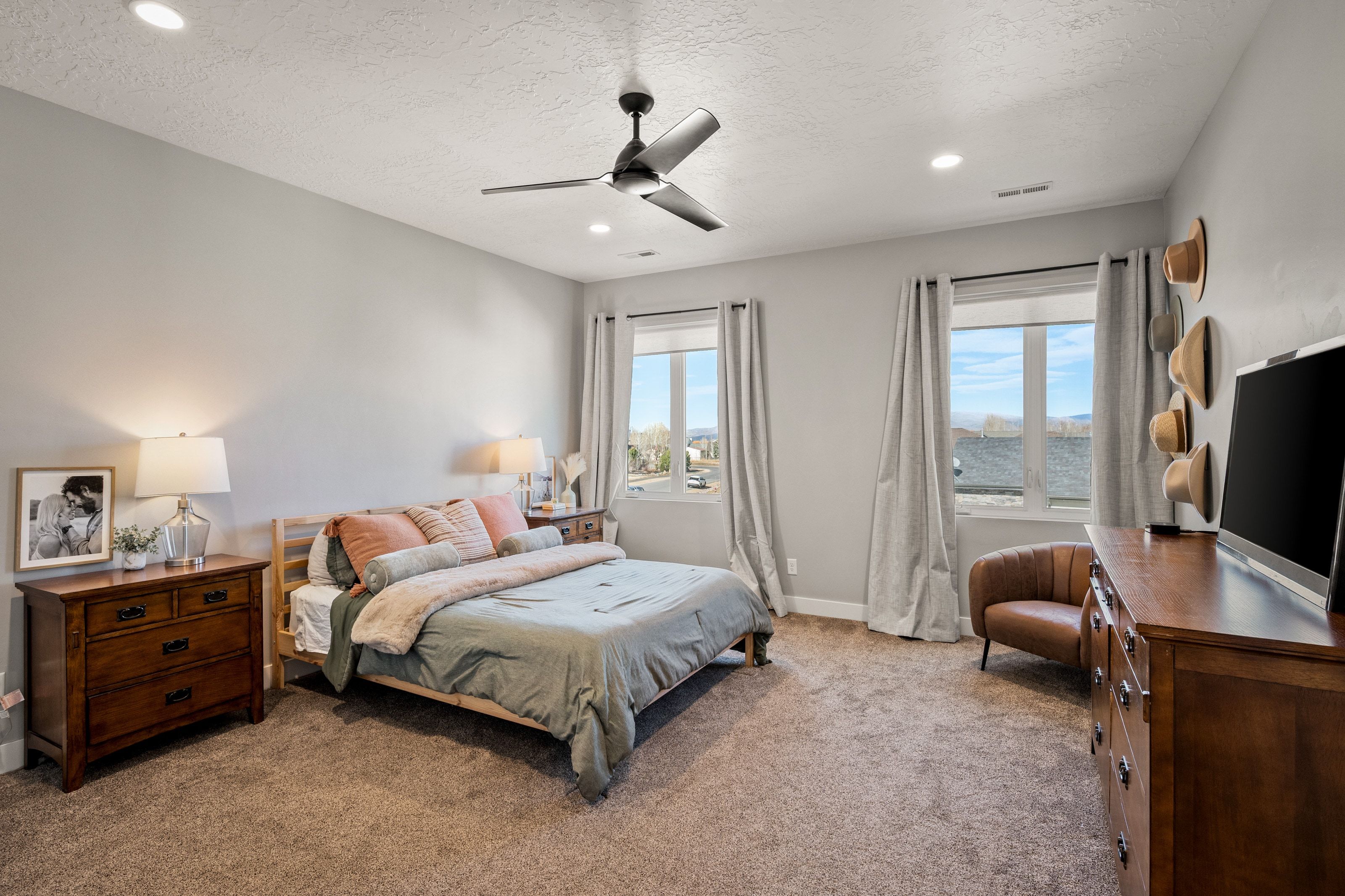 Carpeted room featuring light gray walls, recessed lighting, a ceiling fan, and two large windows with natural light