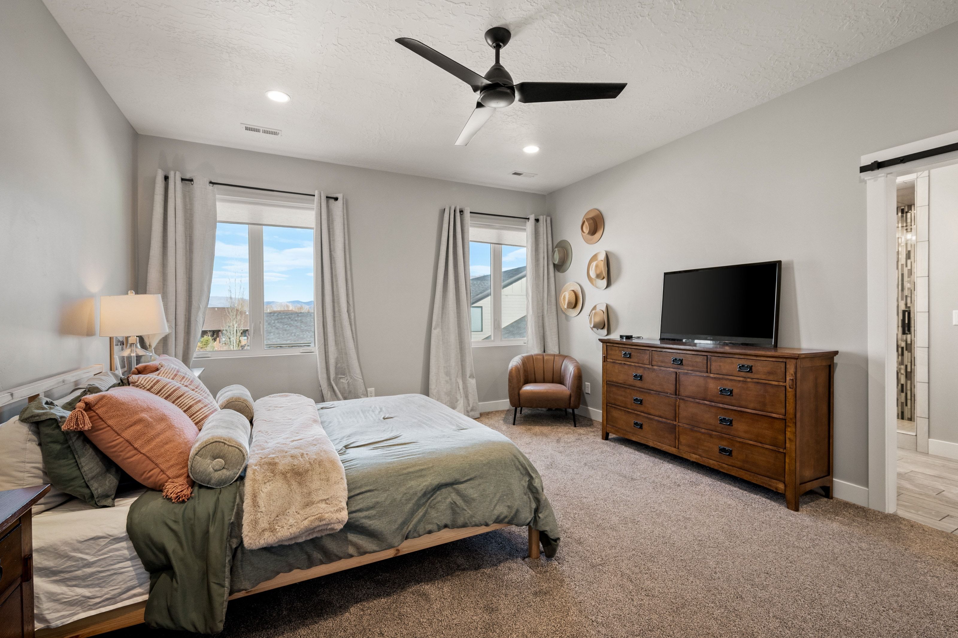 Carpeted bedroom featuring a ceiling fan, recessed lighting, and two windows with outdoor scenery