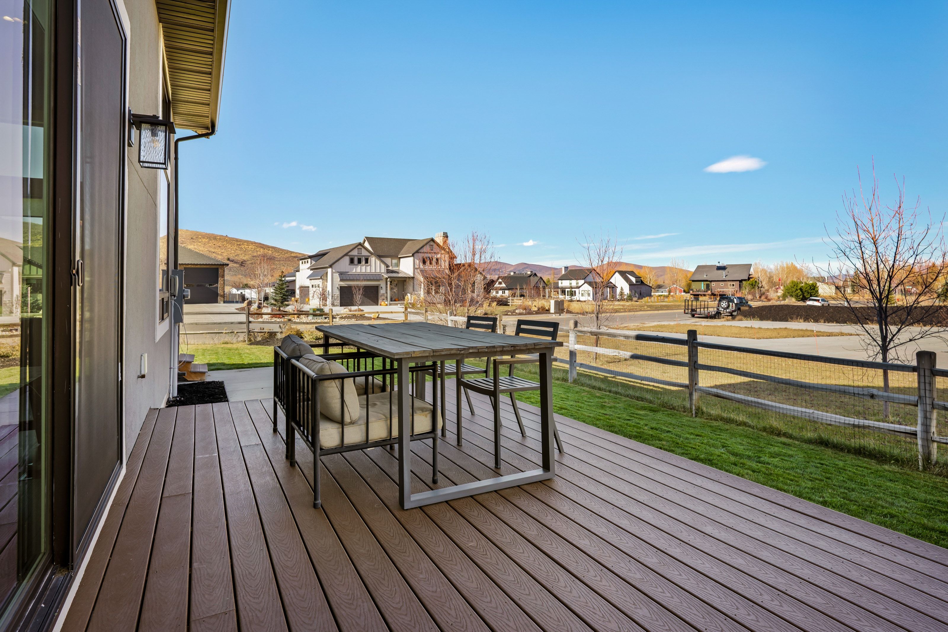 Spacious outdoor deck featuring composite decking, a modern exterior light fixture, and a sliding glass door