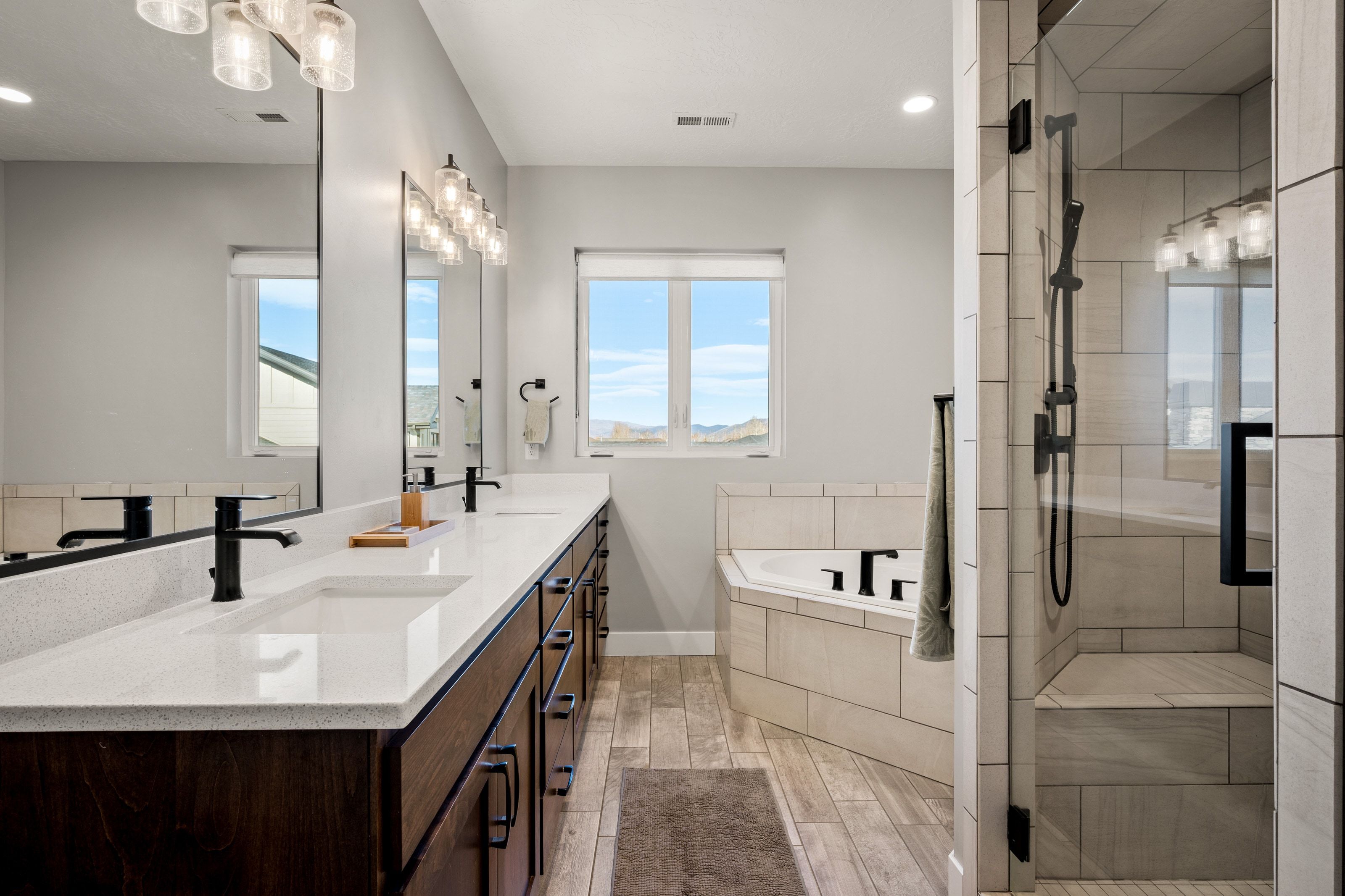 Bathroom featuring an expansive dual vanity with integrated sinks, white countertops, and dark wood-finish cabinetry