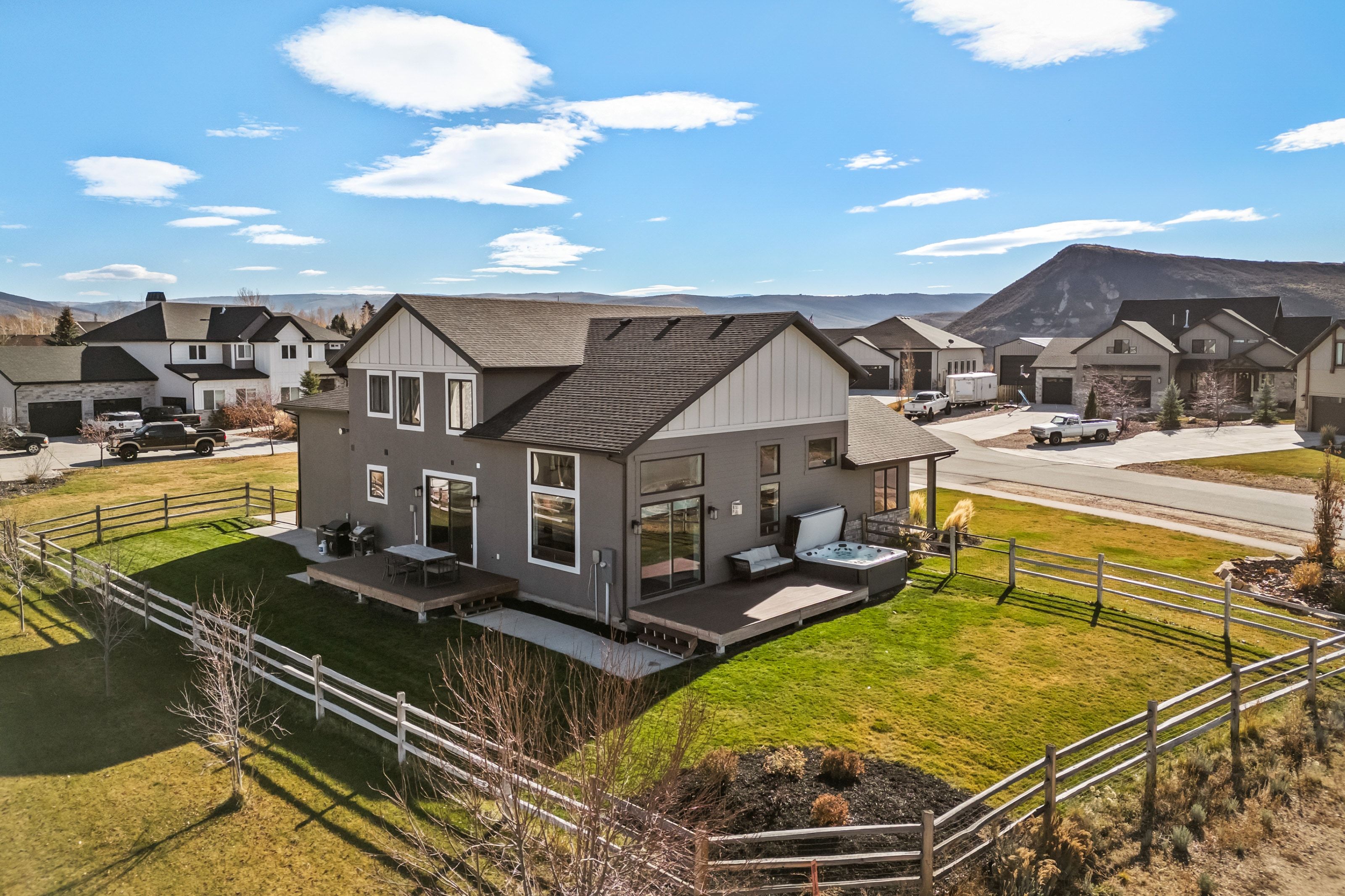 Modern gray exterior with a pitched roof, multiple windows, and a built-in hot tub on a private deck