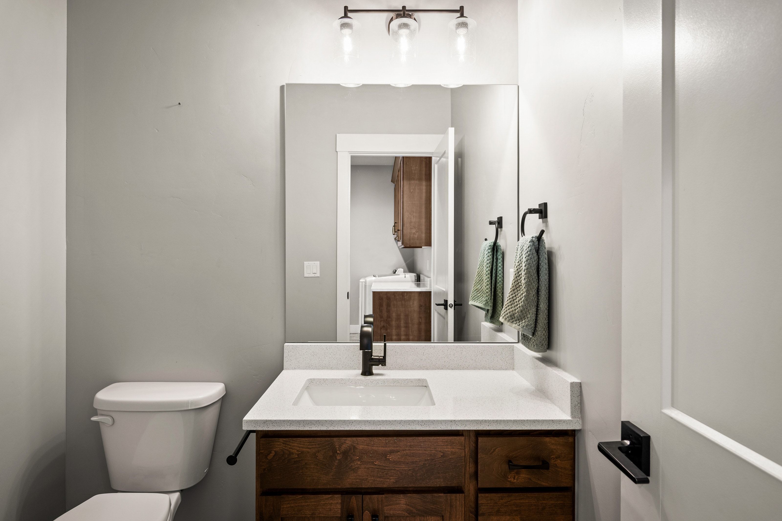 Bathroom vanity with a white countertop and integrated sink, complemented by a dark wood-finish cabinet