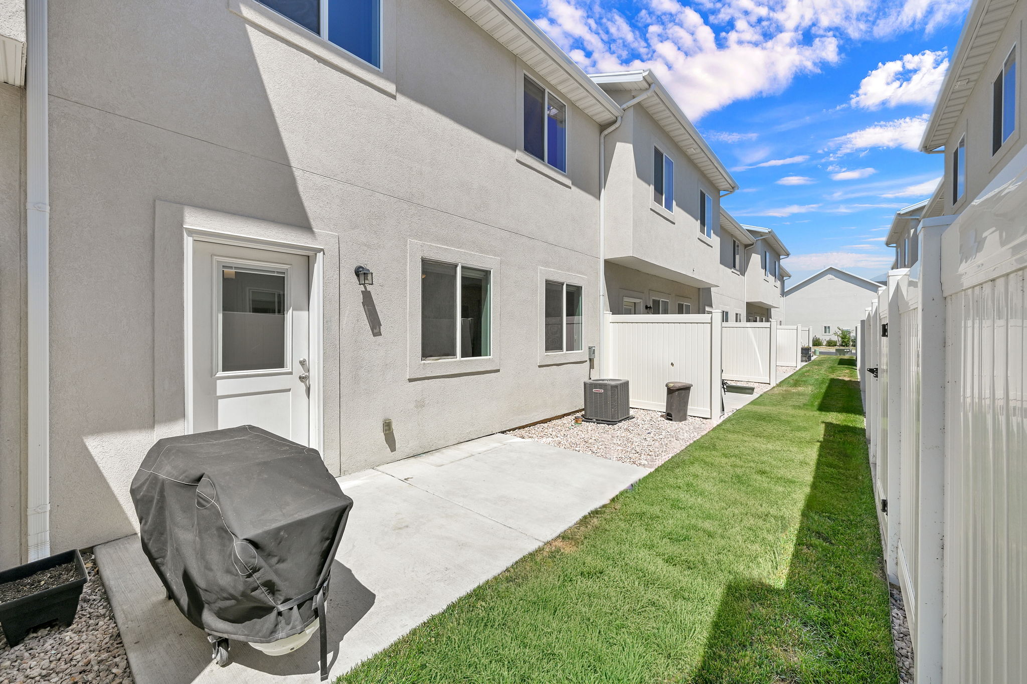 Rear exterior featuring a concrete patio, stucco siding, and a white entry door