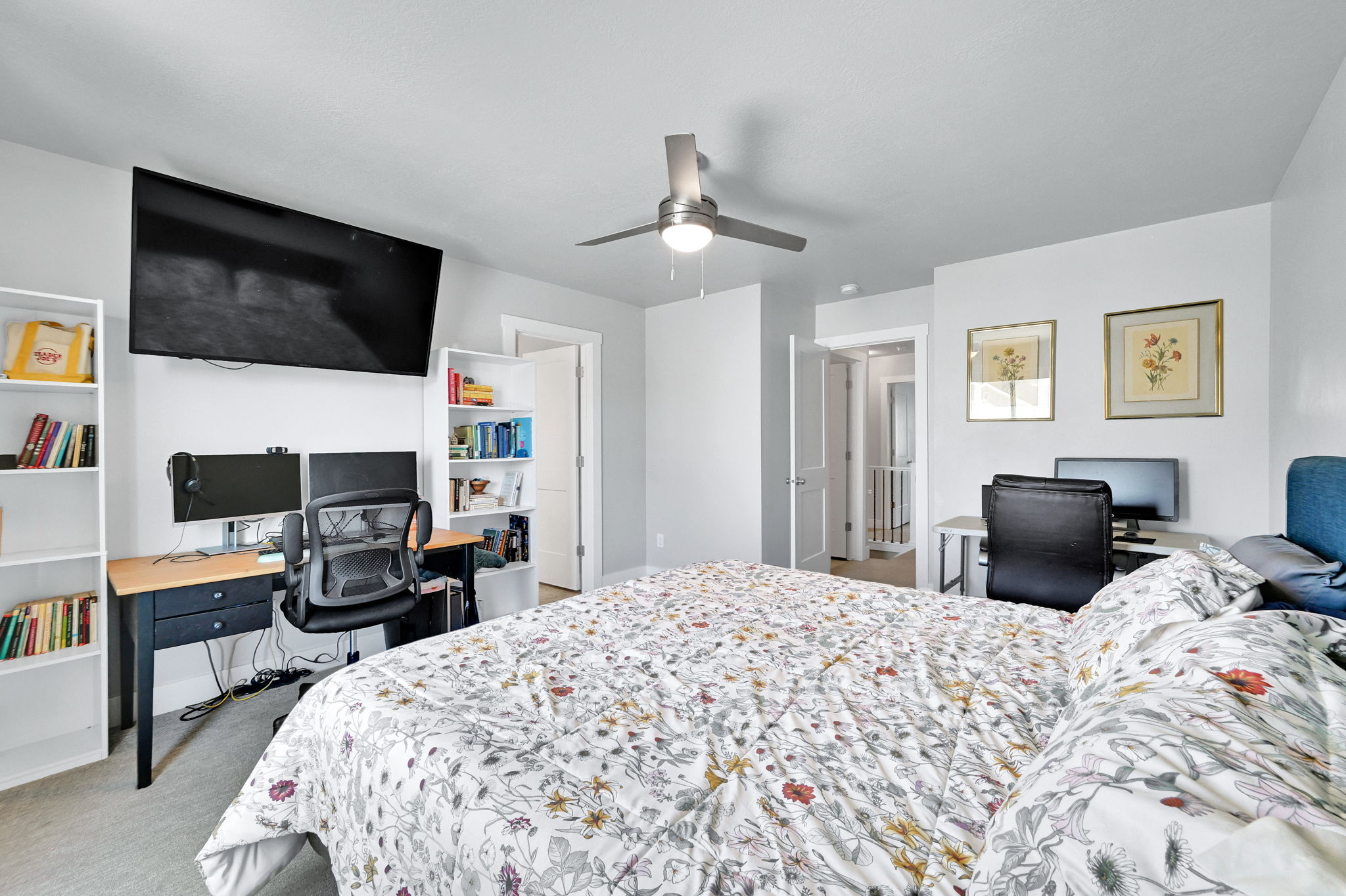 Spacious room featuring light gray walls, a ceiling fan with integrated lighting, and carpeted flooring