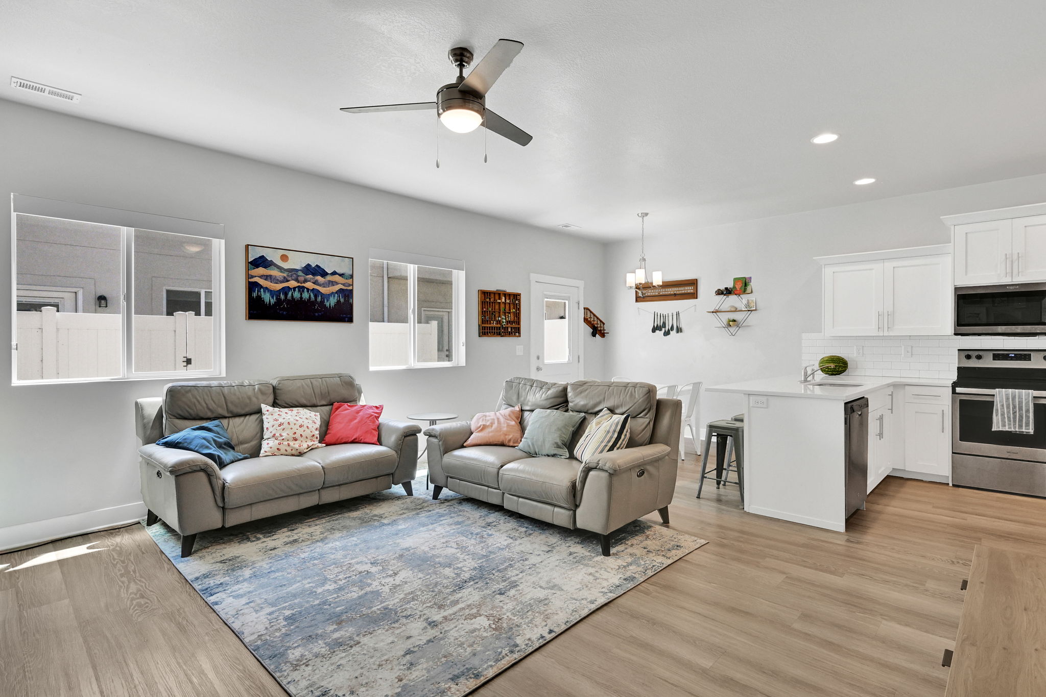 Open-concept living space with wood-finish flooring, a contemporary ceiling fan, and recessed lighting