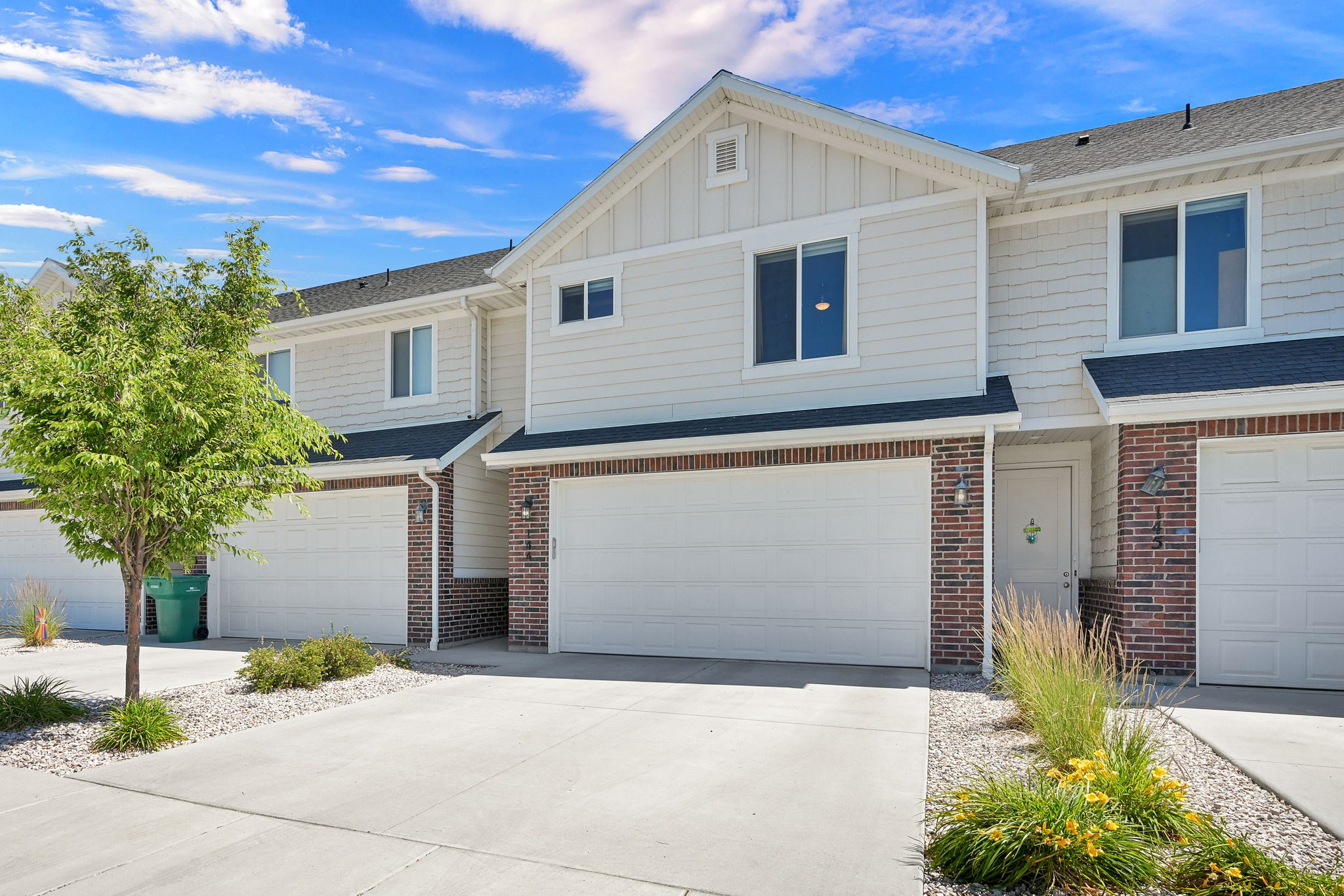 Townhome exterior featuring light-colored siding, brick accents, and a composition shingle roof
