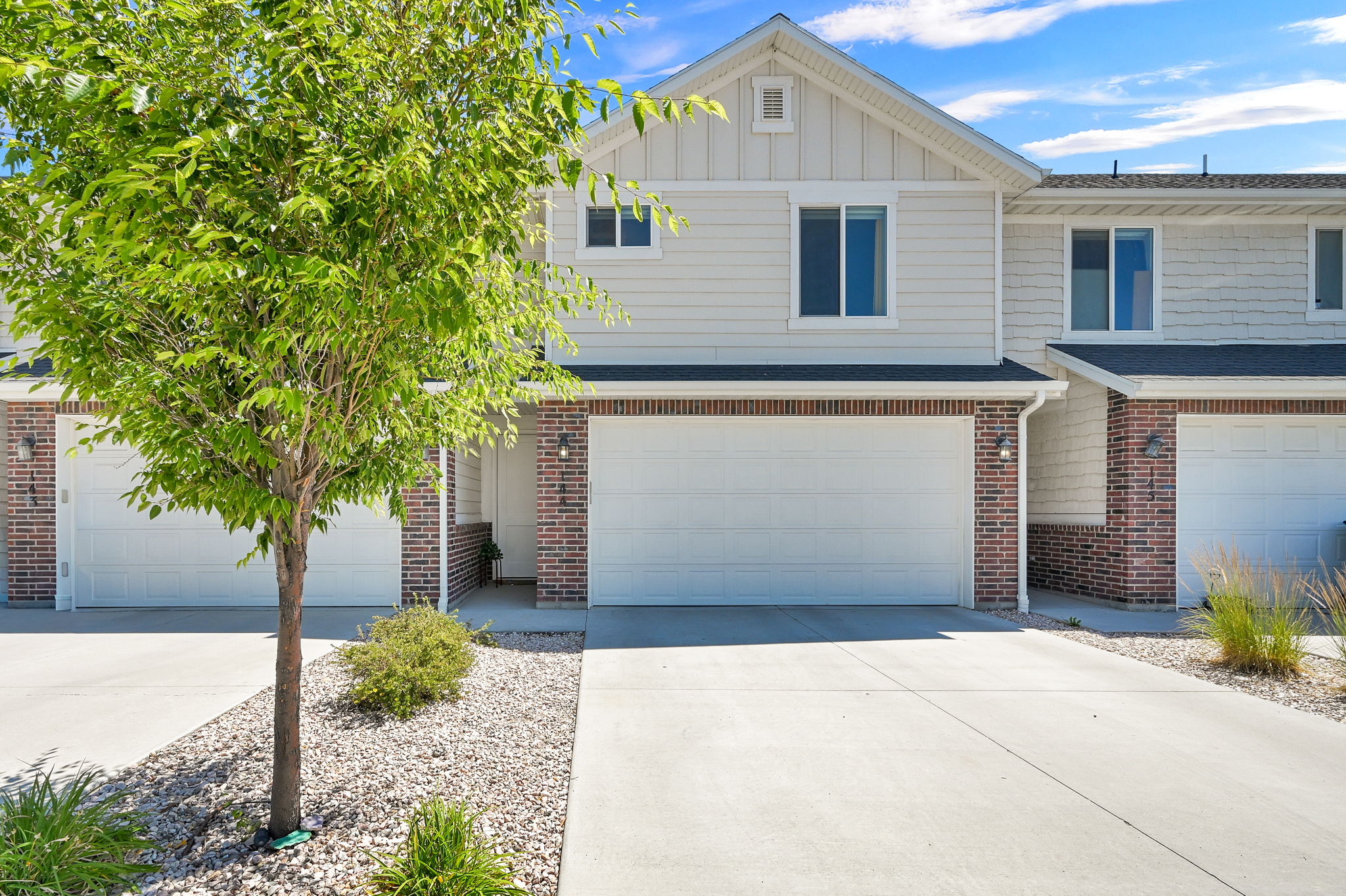 Modern townhome exterior featuring light-colored siding and brick accents