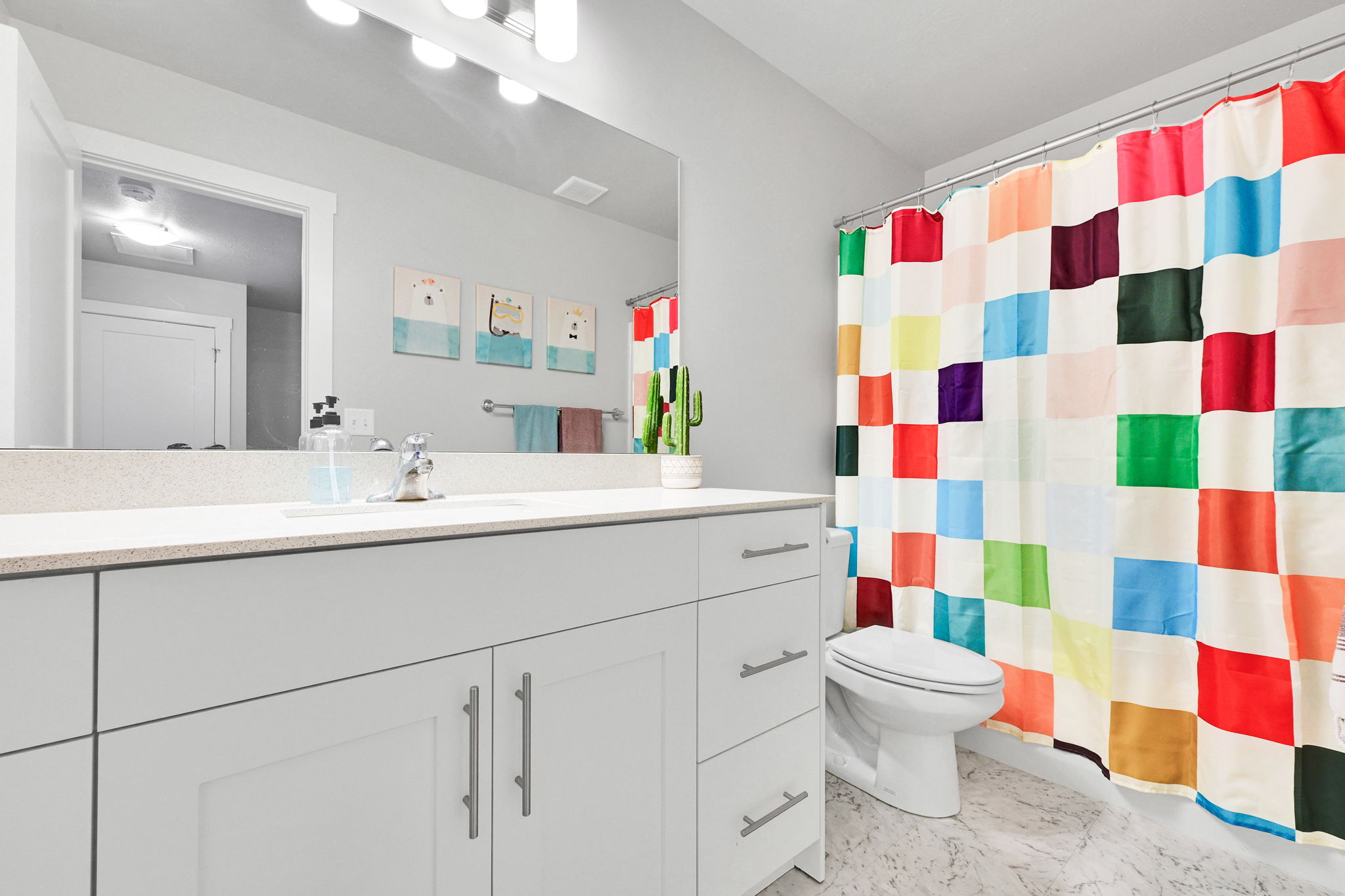 Contemporary bathroom featuring a light gray vanity with ample storage, a solid surface countertop, an undermount sink, and a large mirror