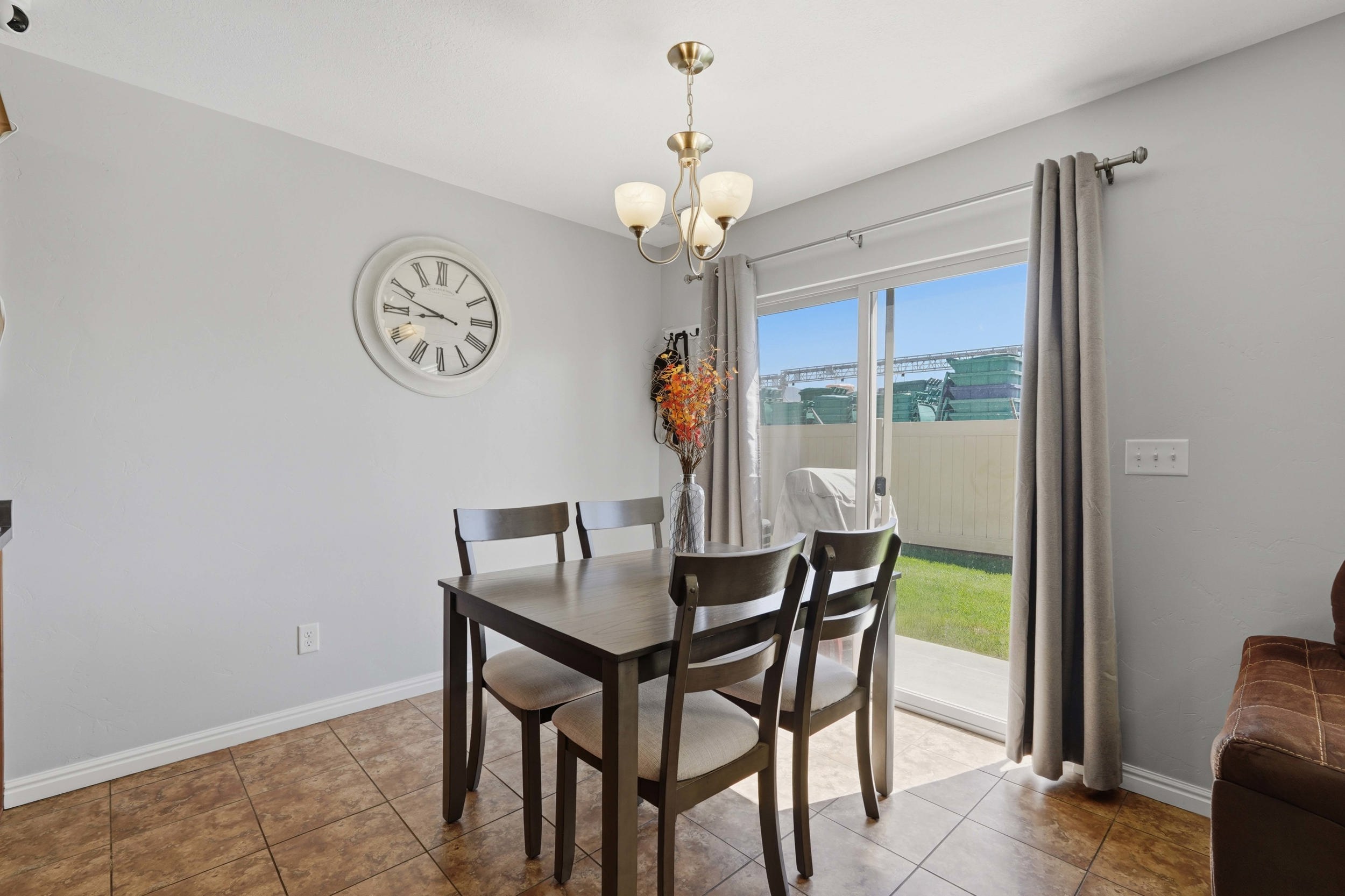 Dining area featuring tile flooring, a brass-finish chandelier, and light gray wall paint