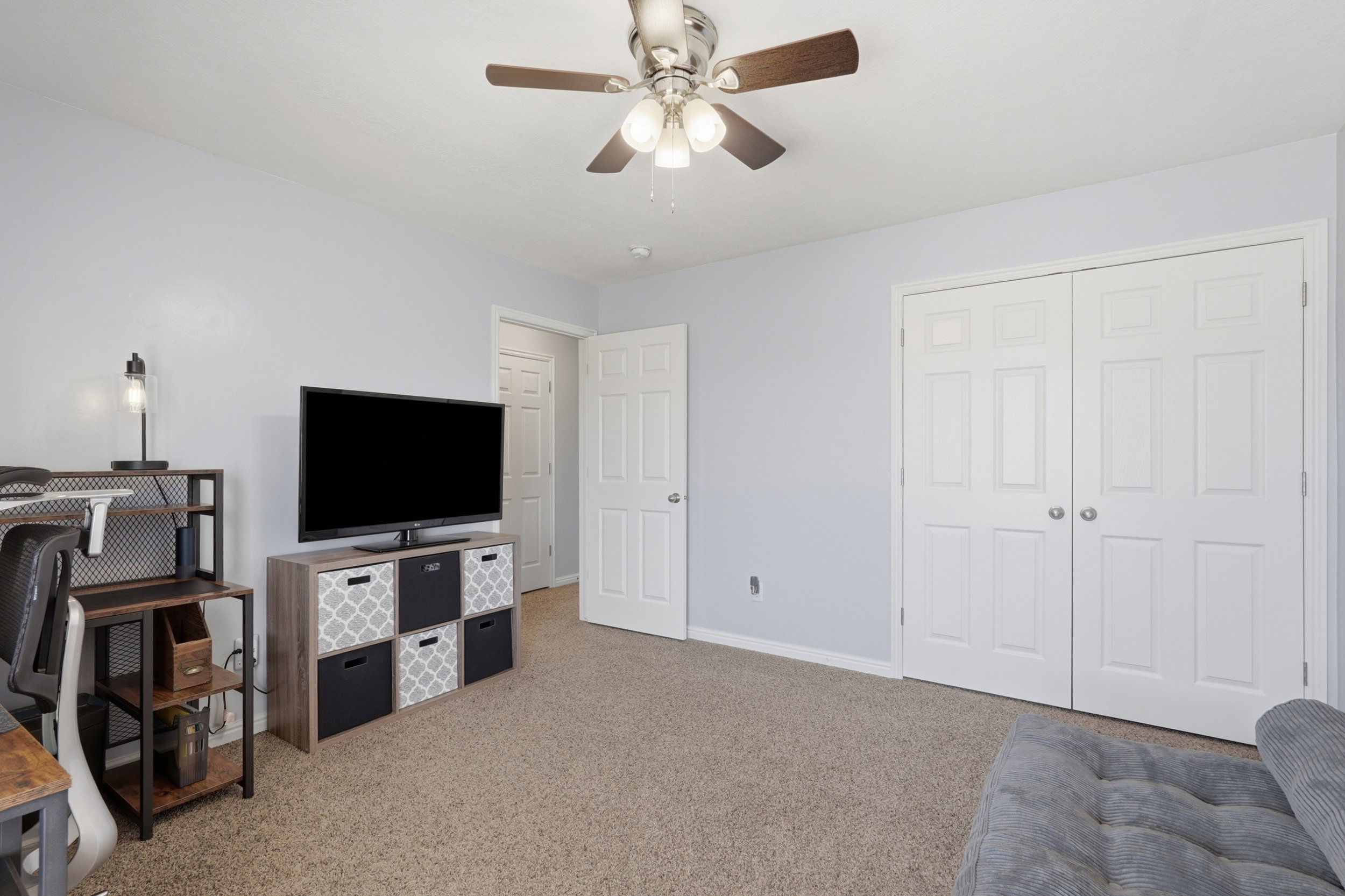 Carpeted room with a ceiling fan, light blue walls, and white trim