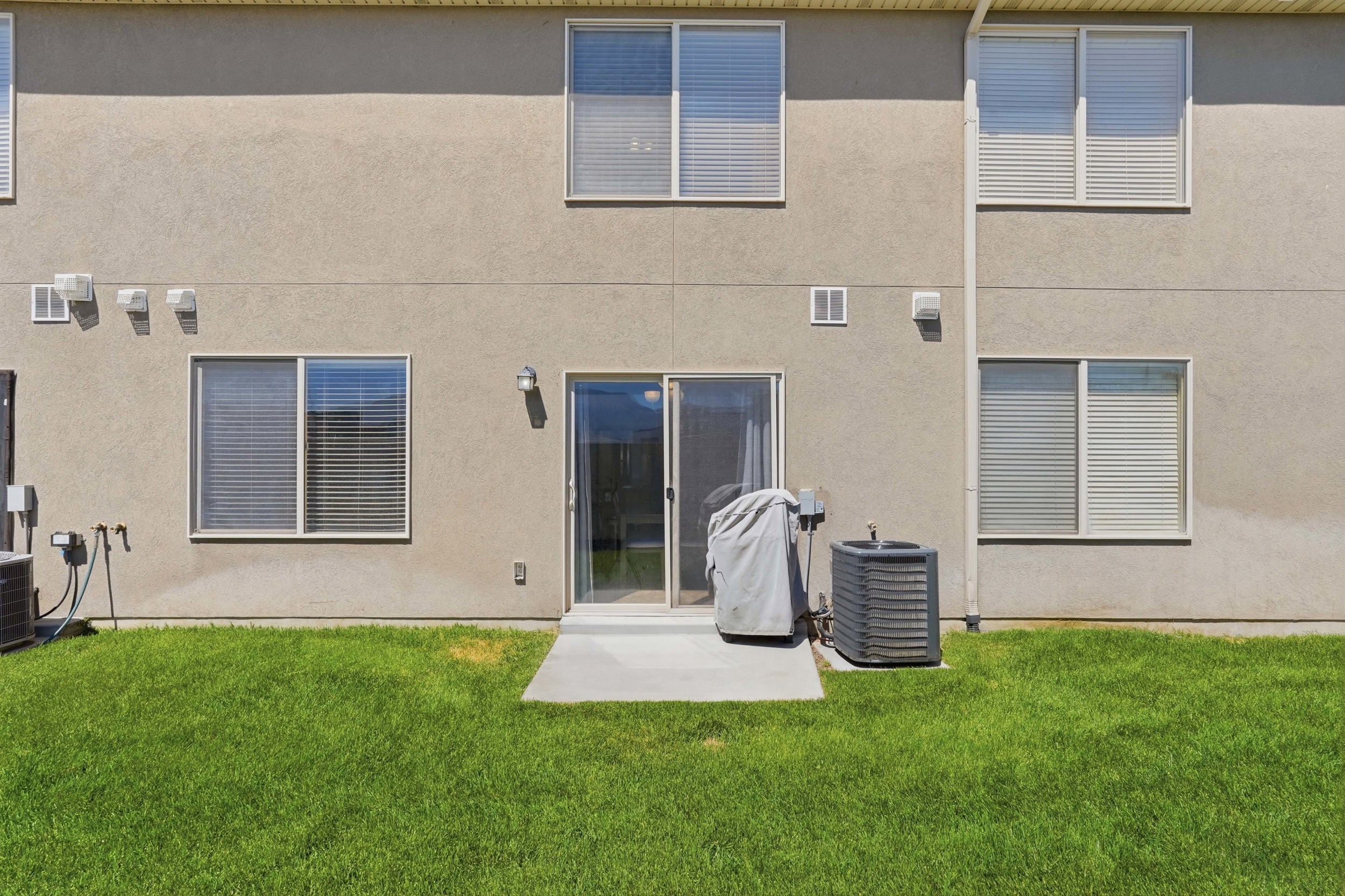 Rear exterior with stucco siding and a lush green lawn