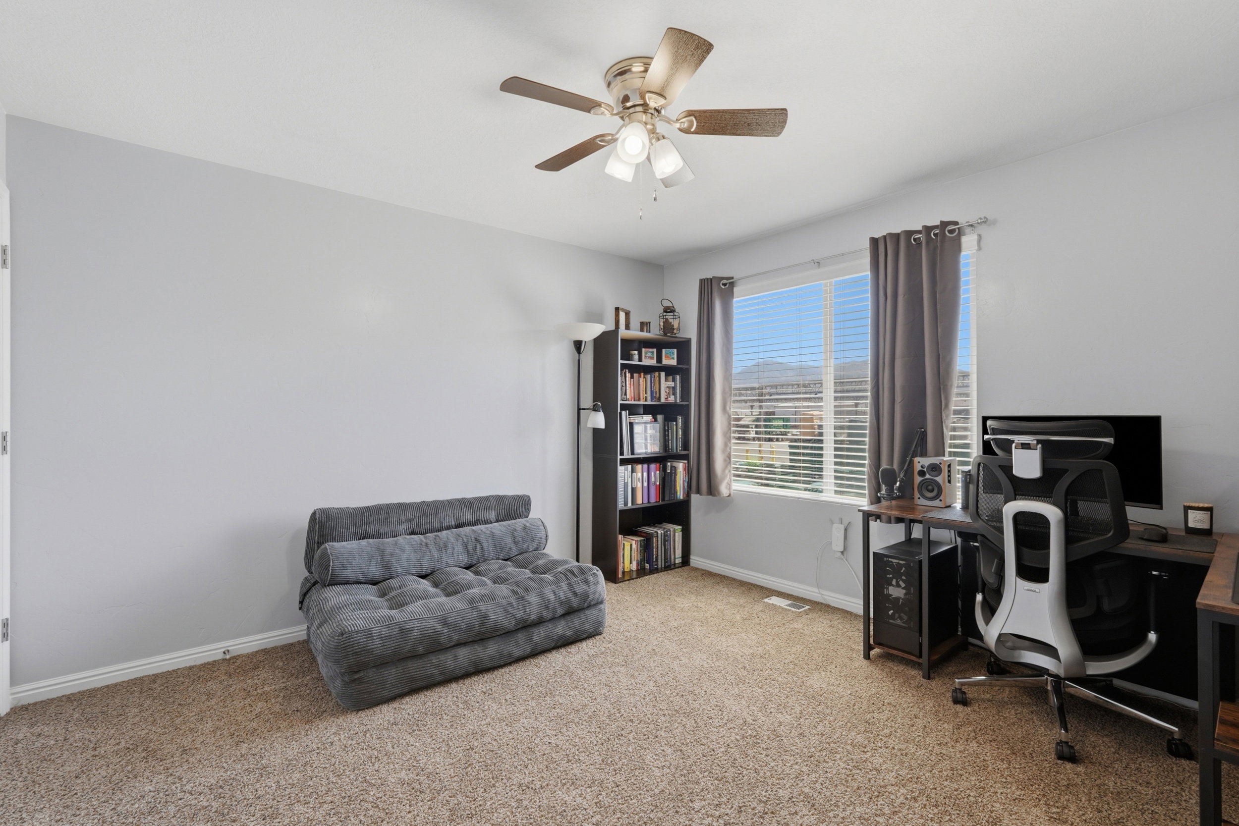 Carpeted room featuring light gray walls and a ceiling fan with integrated lighting