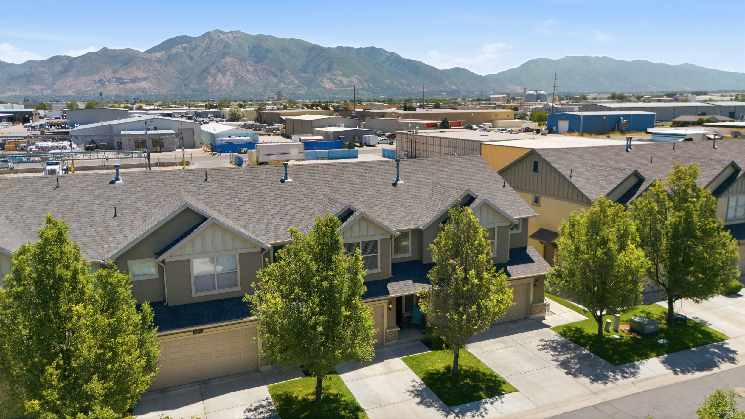 Modern townhome exterior featuring an attached garage, landscaped front yard, and a clear mountain backdrop