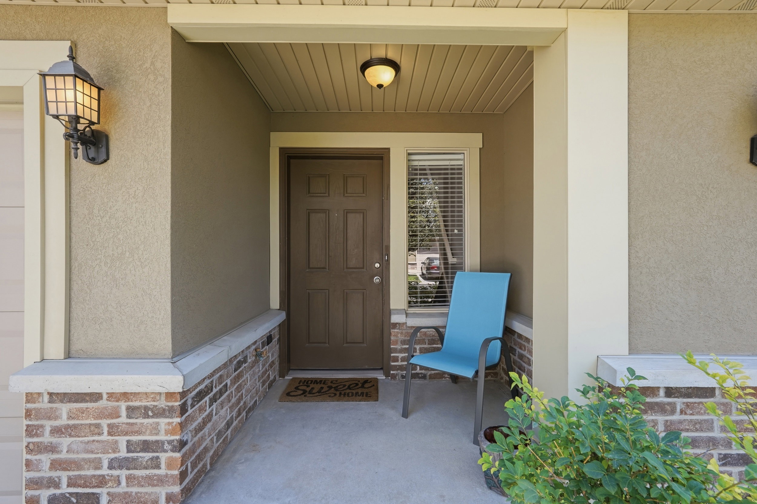 Covered front entry featuring a paneled door, sidelight window with blinds, and concrete flooring