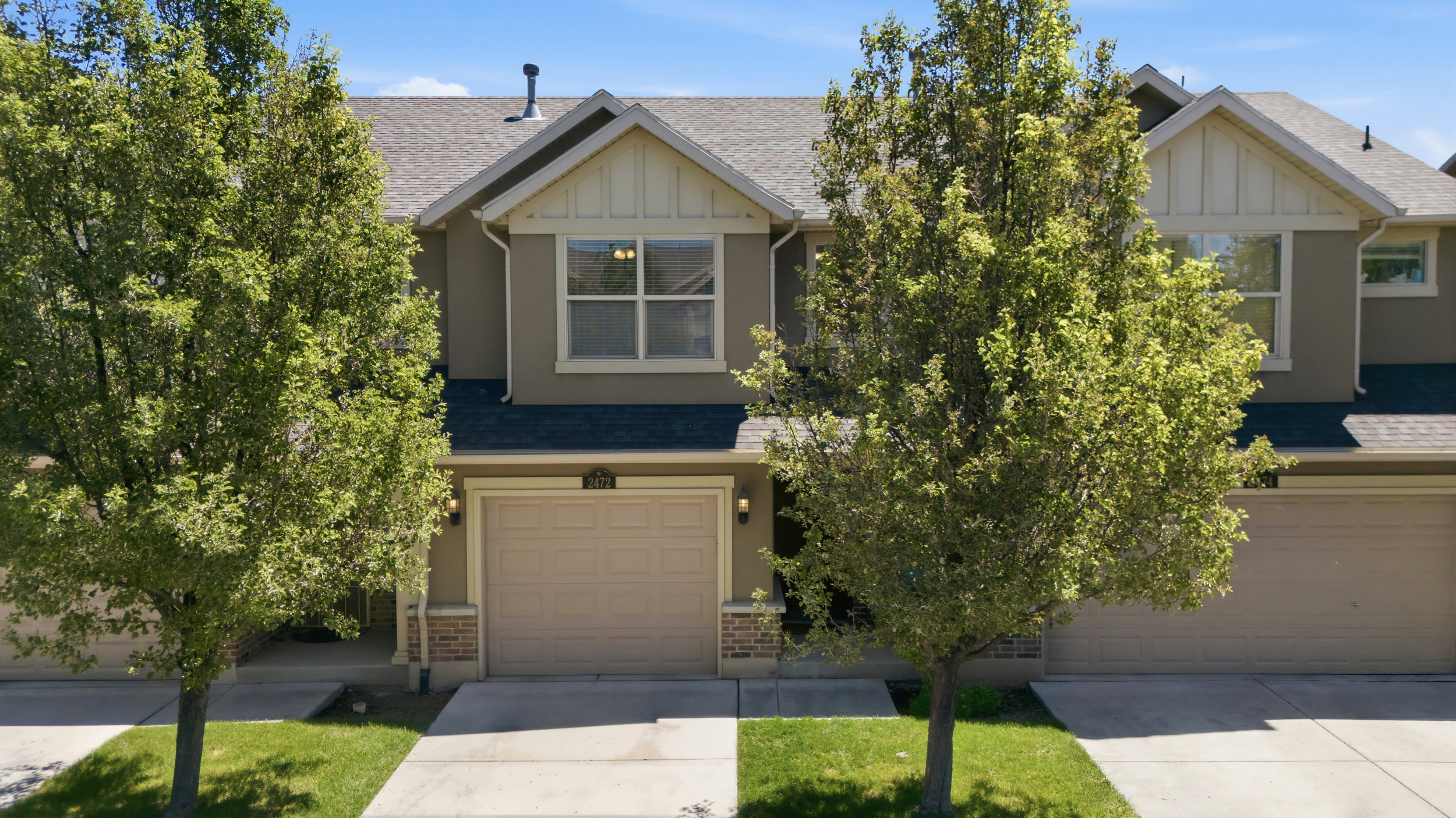 Townhome exterior featuring a neutral stucco facade and a two-car garage