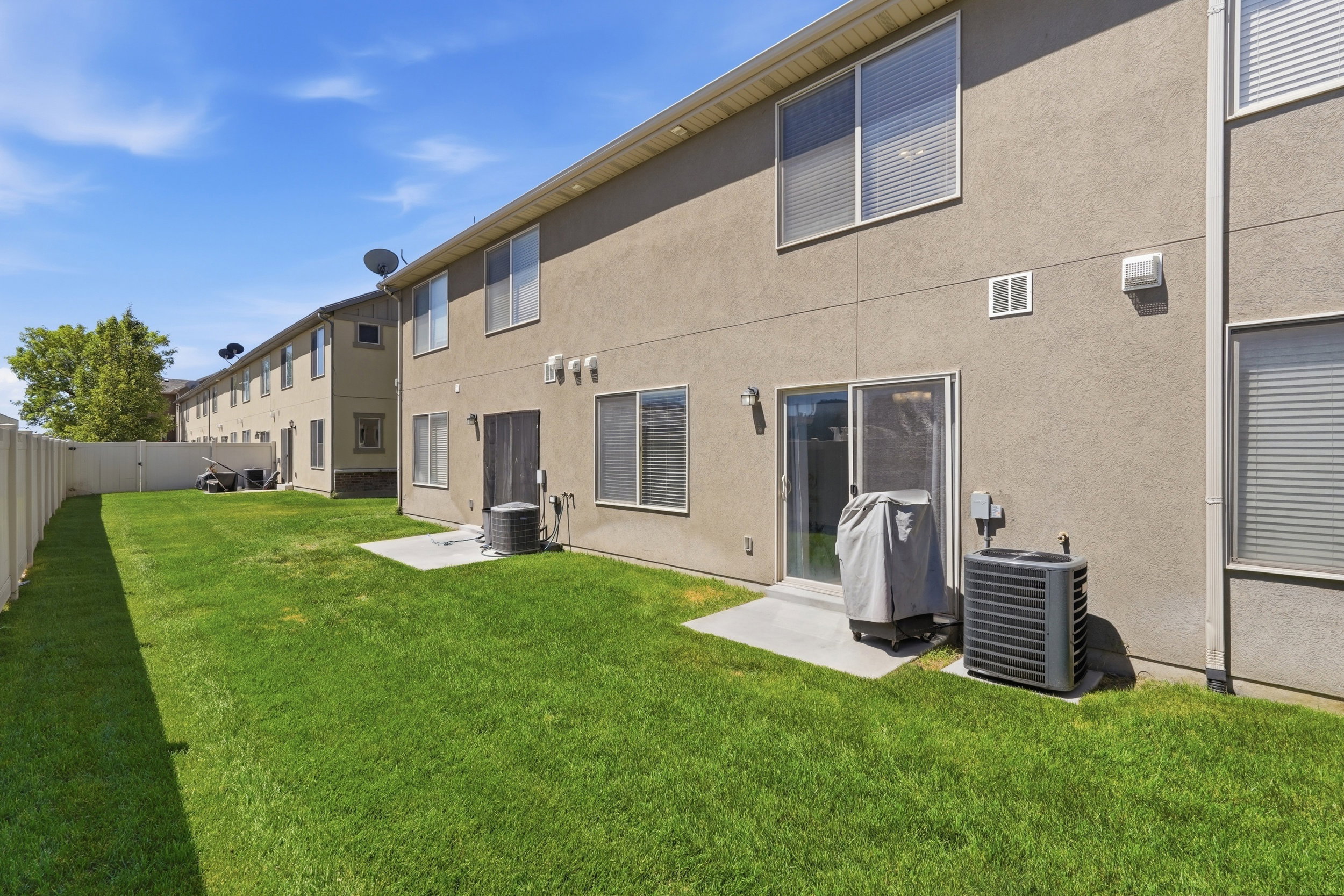 Expansive green lawn with a white privacy fence