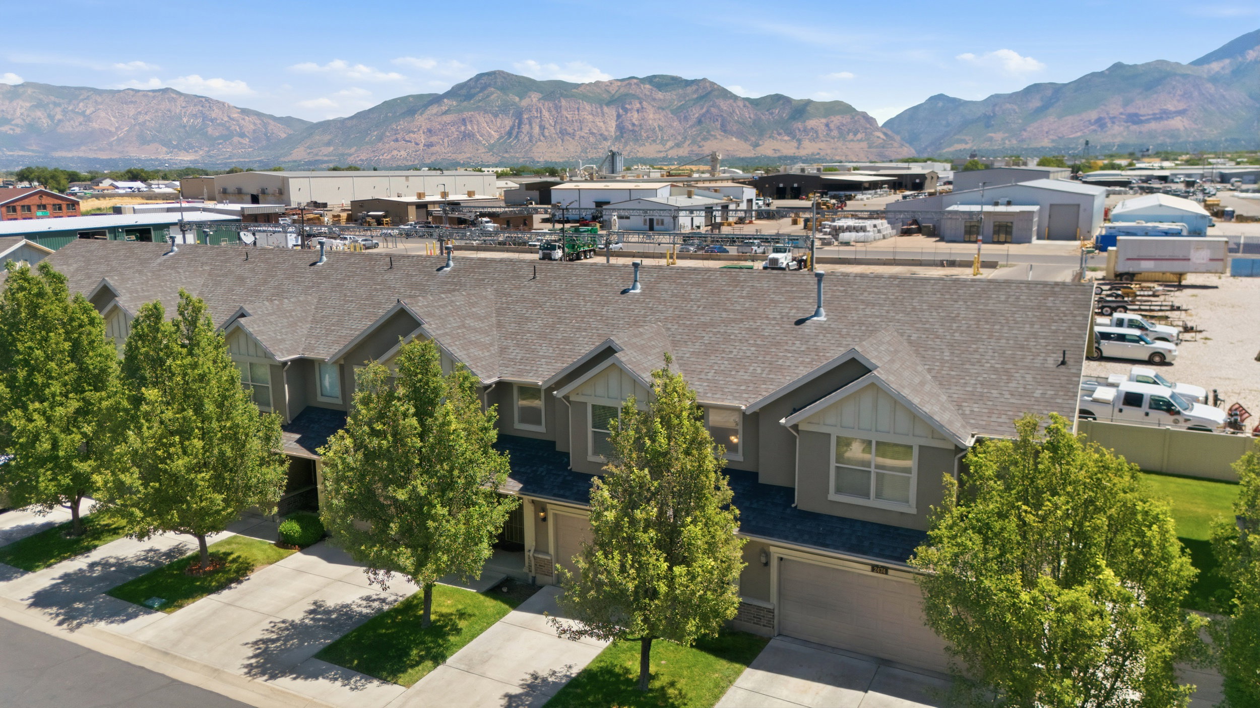 Row of townhomes featuring gabled roofs, light grey siding, and individual driveways