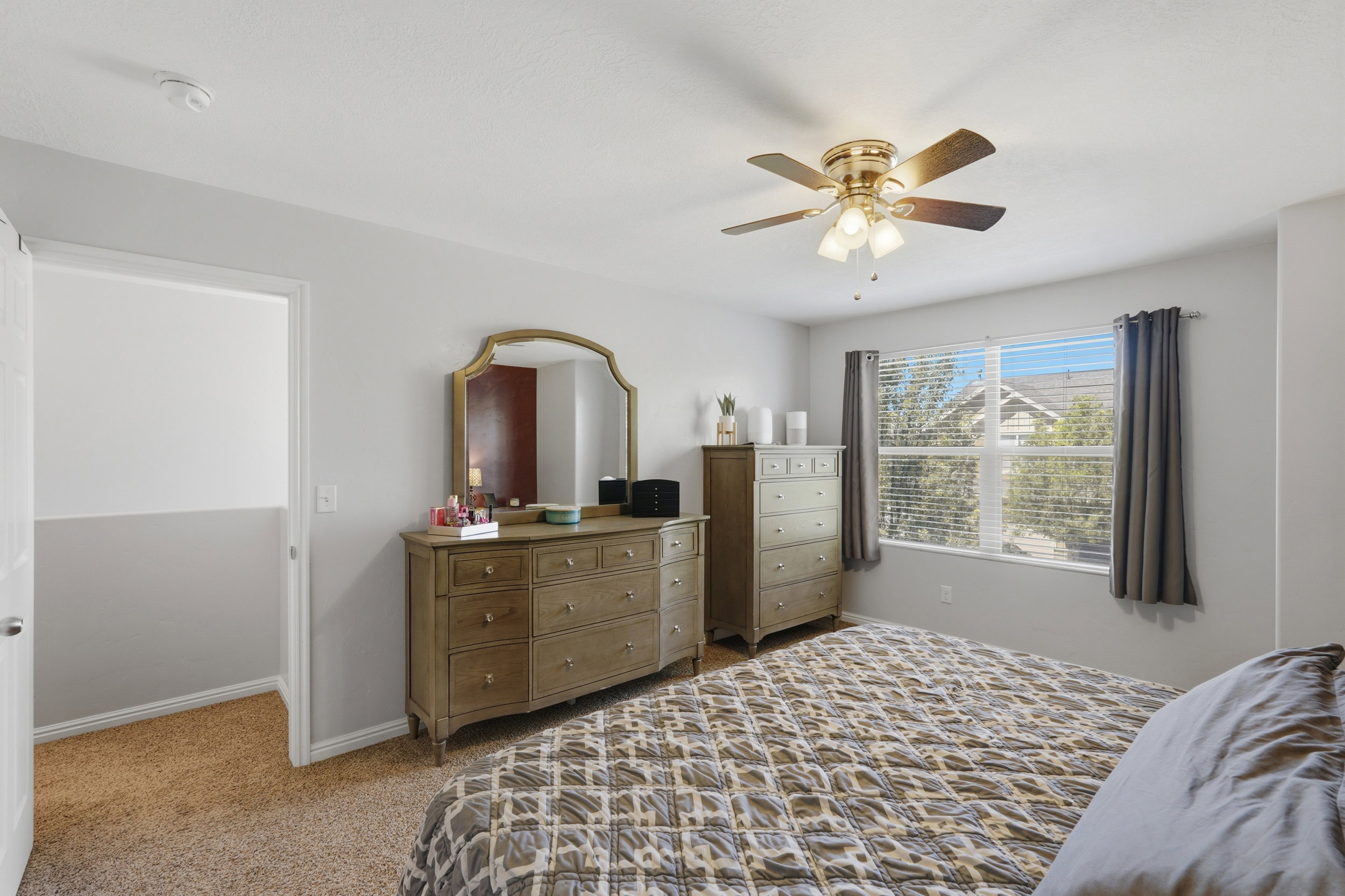Carpeted room featuring a ceiling fan with integrated lighting, a window with blinds and drapes, and neutral wall tones