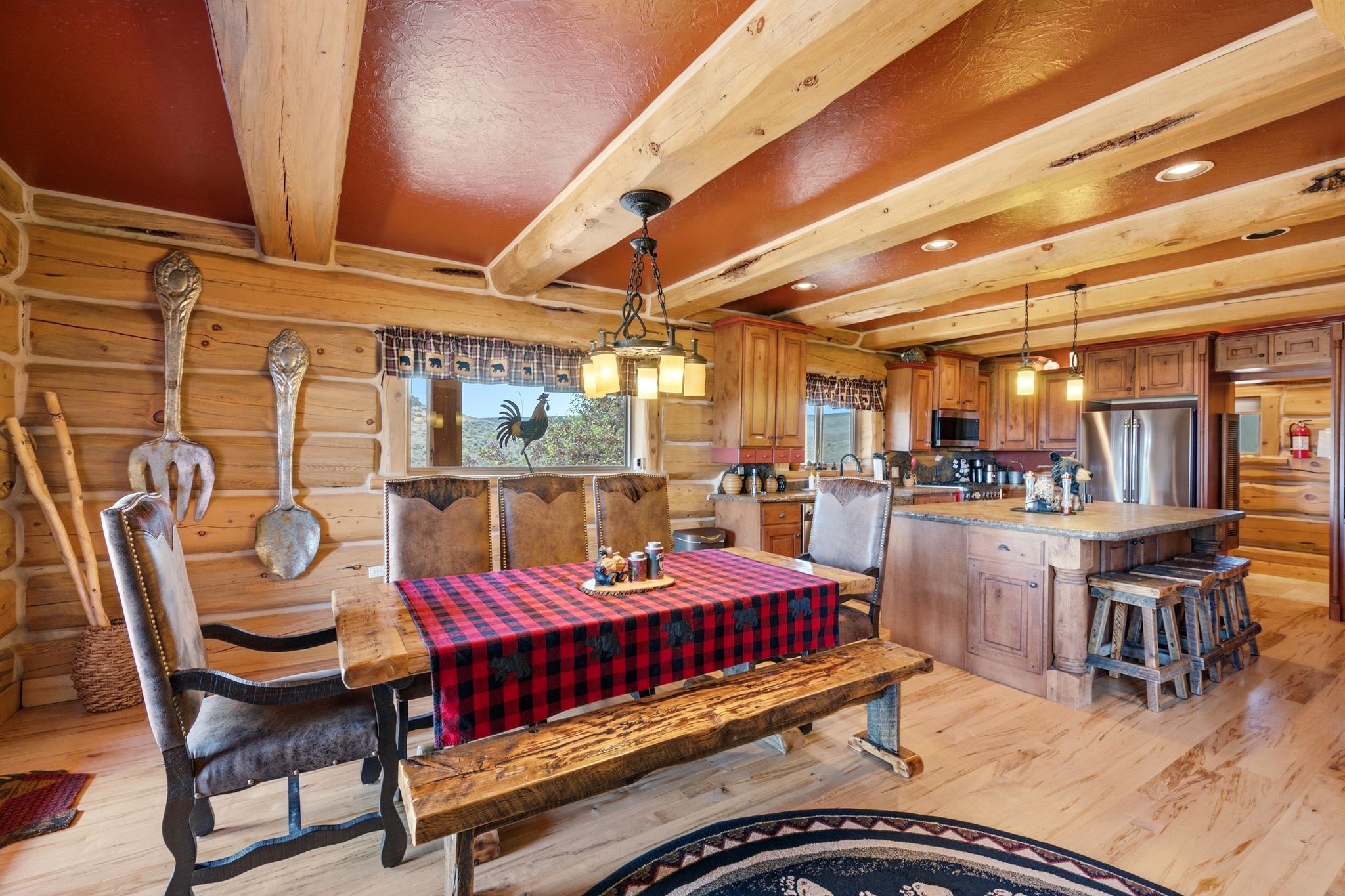 Open-concept living space featuring wood-finish flooring, exposed log walls, and a wood-beamed ceiling with recessed lighting