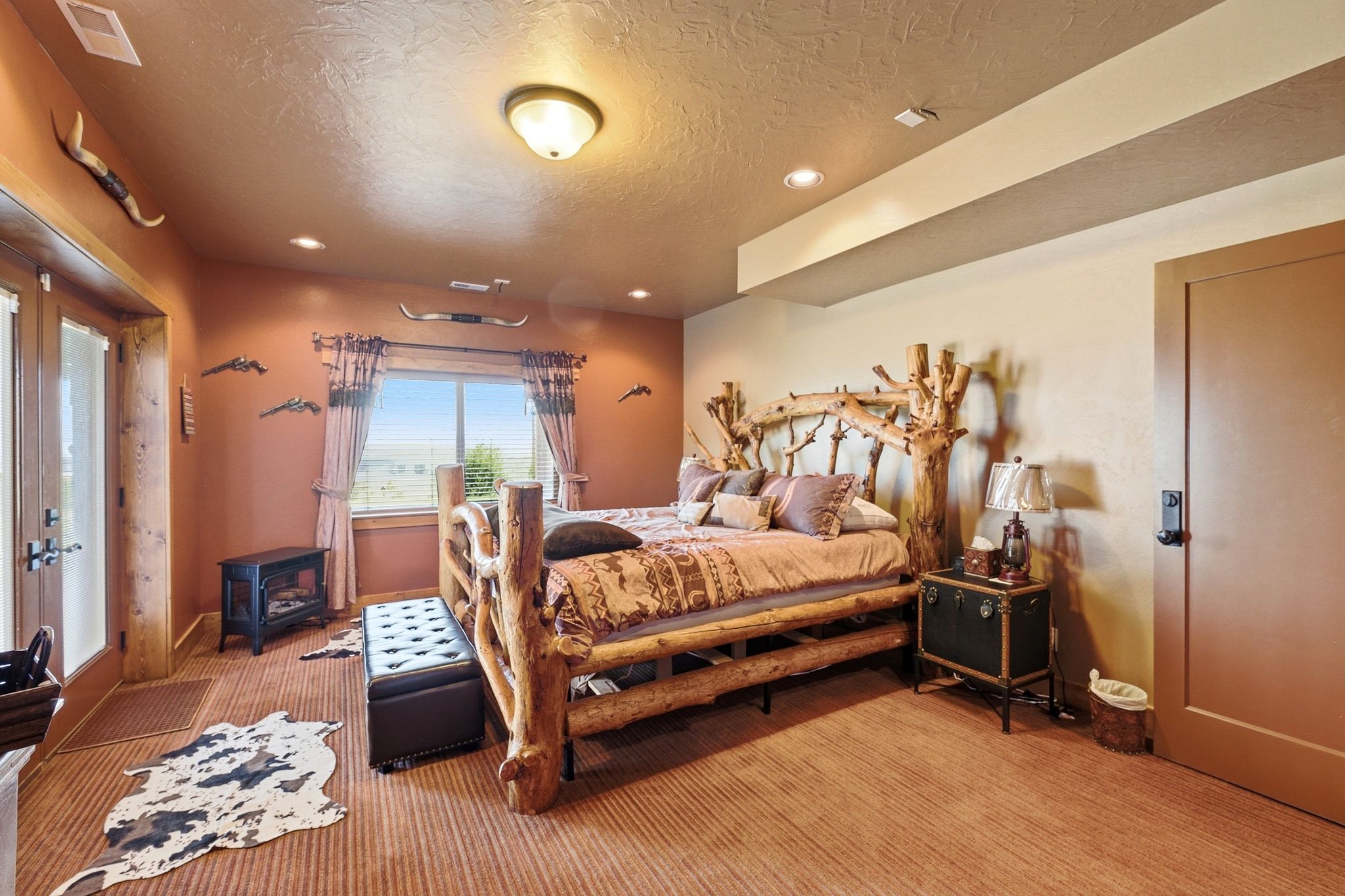 Bedroom featuring a log-style bed frame, warm wall tones, and recessed lighting