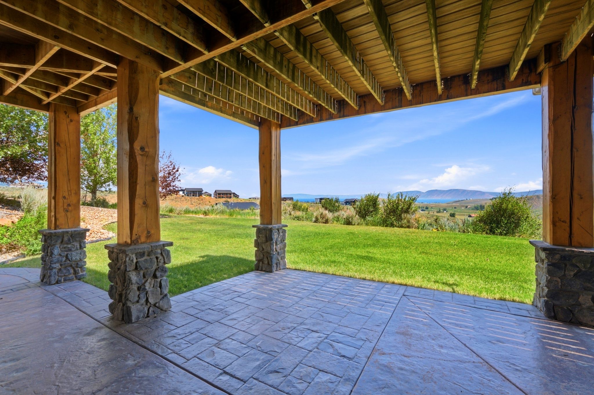 Covered patio with stamped concrete flooring, supported by robust wood posts with stone bases