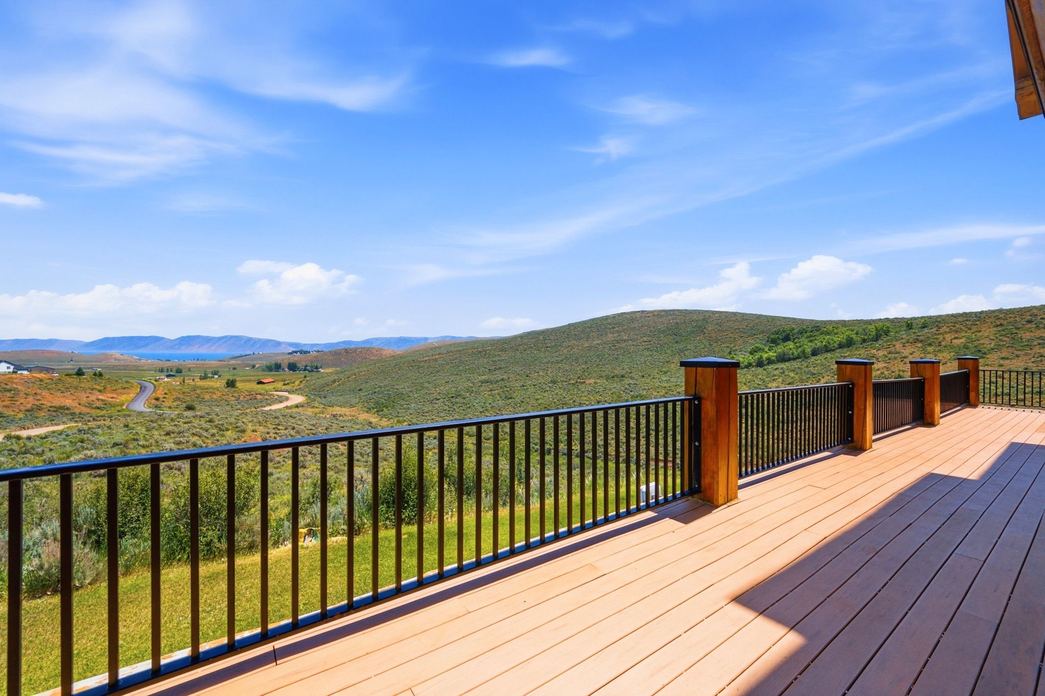 Spacious outdoor deck featuring composite decking, black metal railings, and wood-wrapped posts