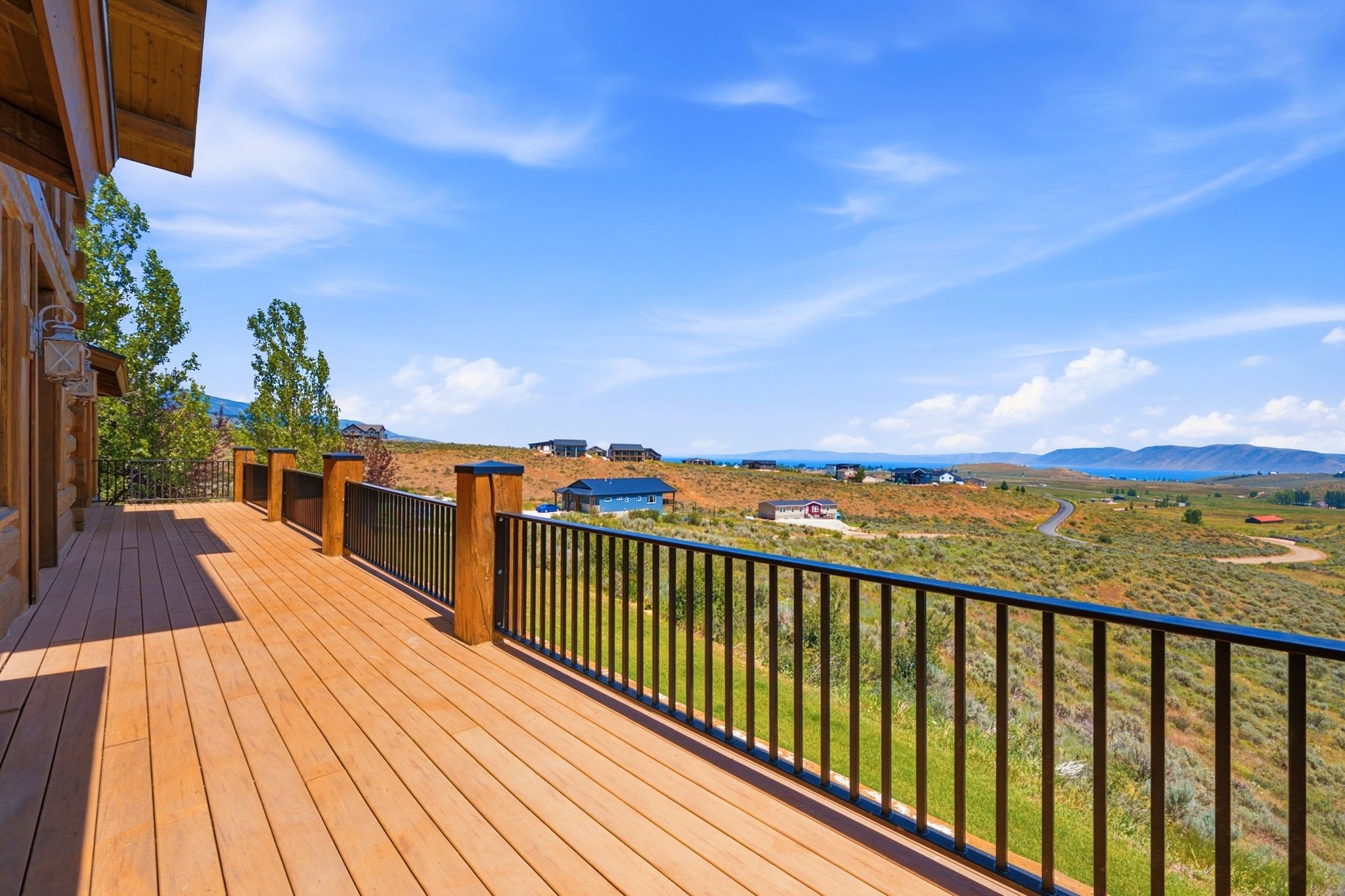 Expansive outdoor deck featuring wood-finish flooring and black metal railings with wood posts