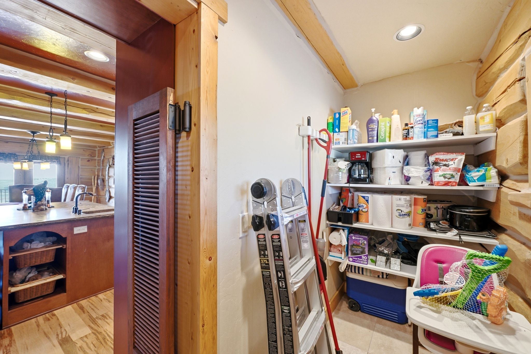 Pantry featuring built-in shelving, recessed lighting, and log wall accents