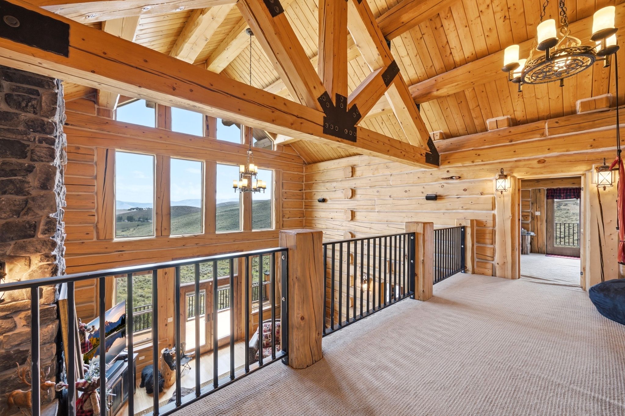 Open-concept upper level featuring exposed wood beams and log walls