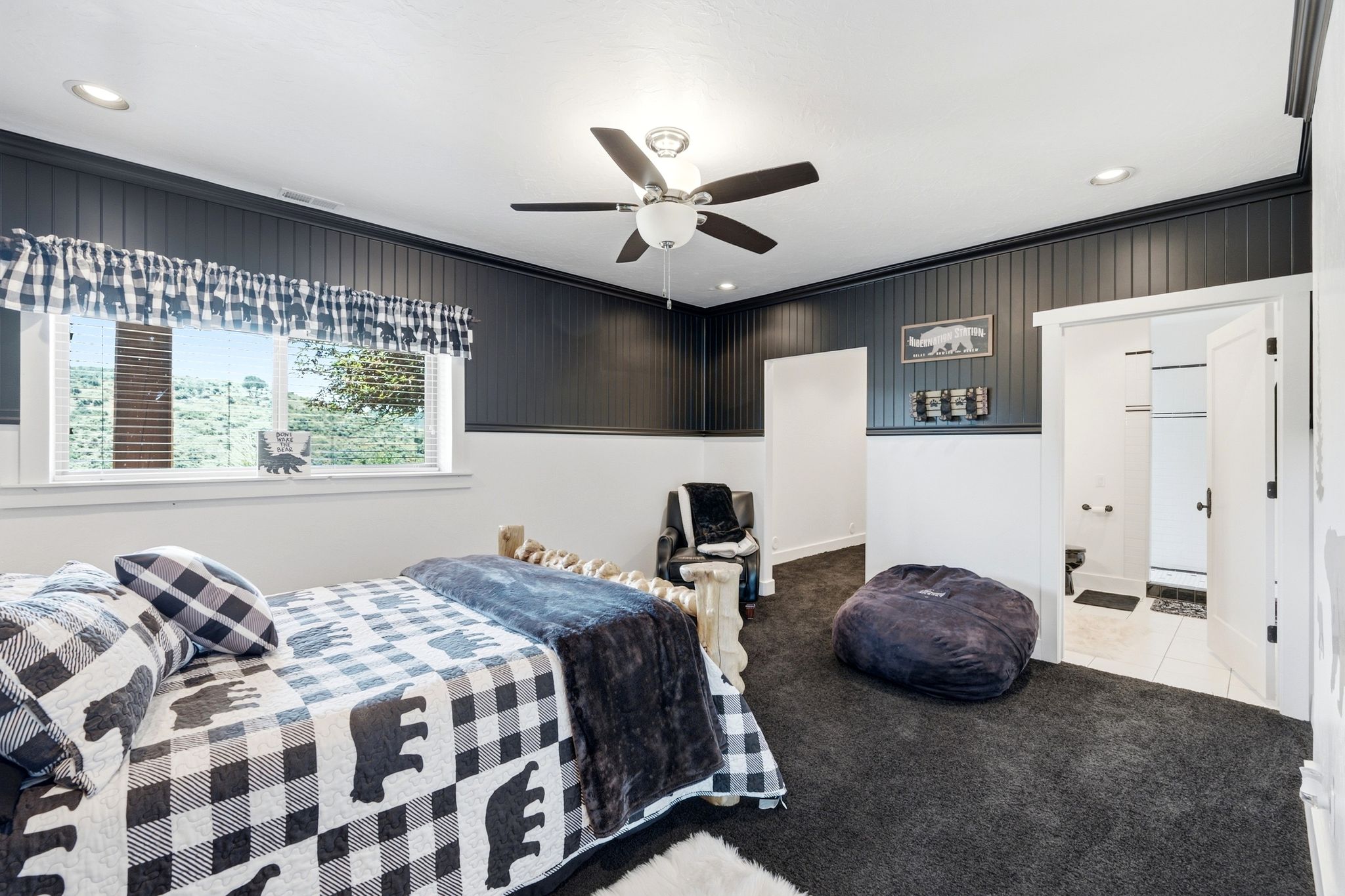 Room featuring dark paneled wainscoting, white walls, and dark carpet flooring