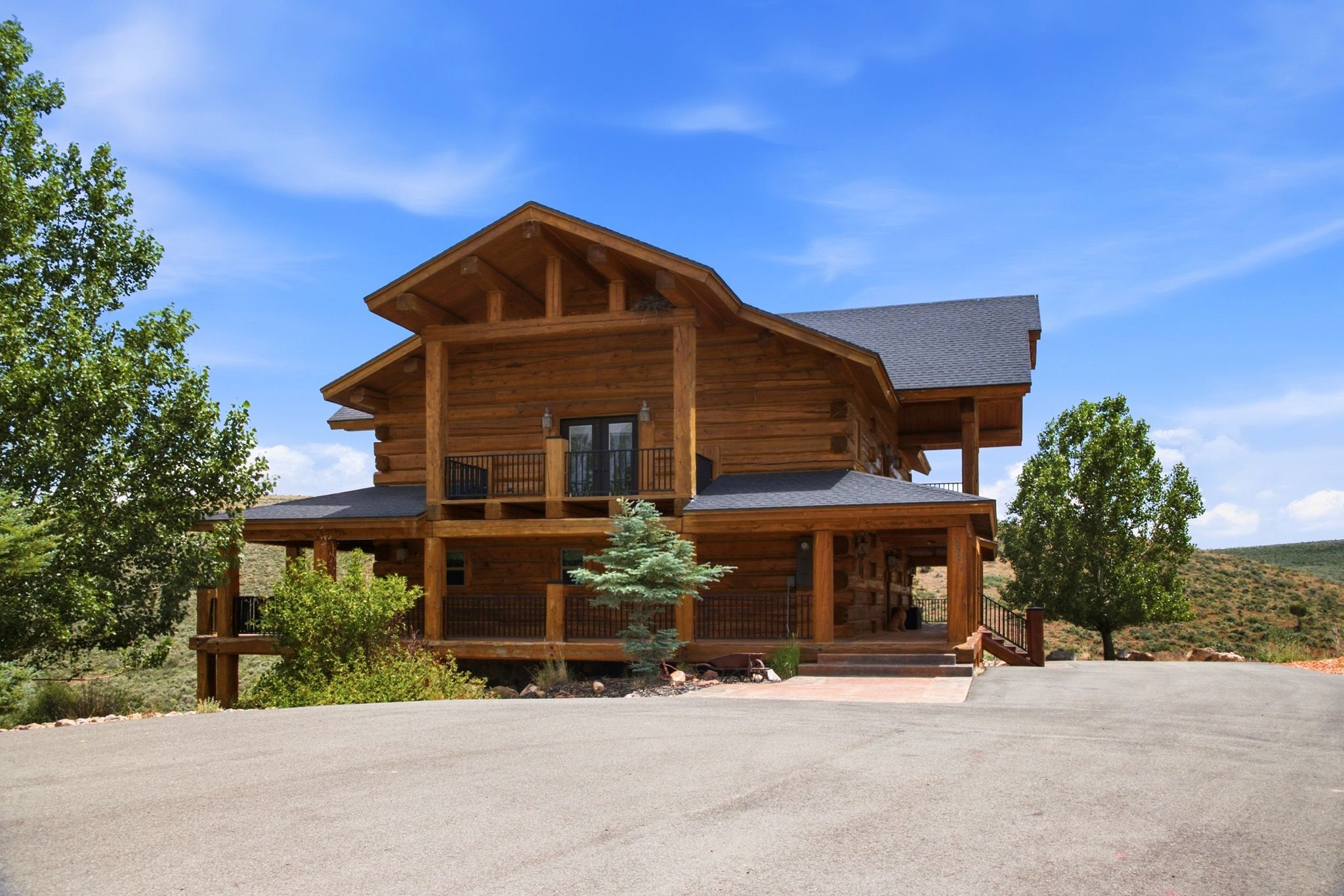 Log cabin exterior featuring a covered porch, upper-level balcony, and exposed beam construction