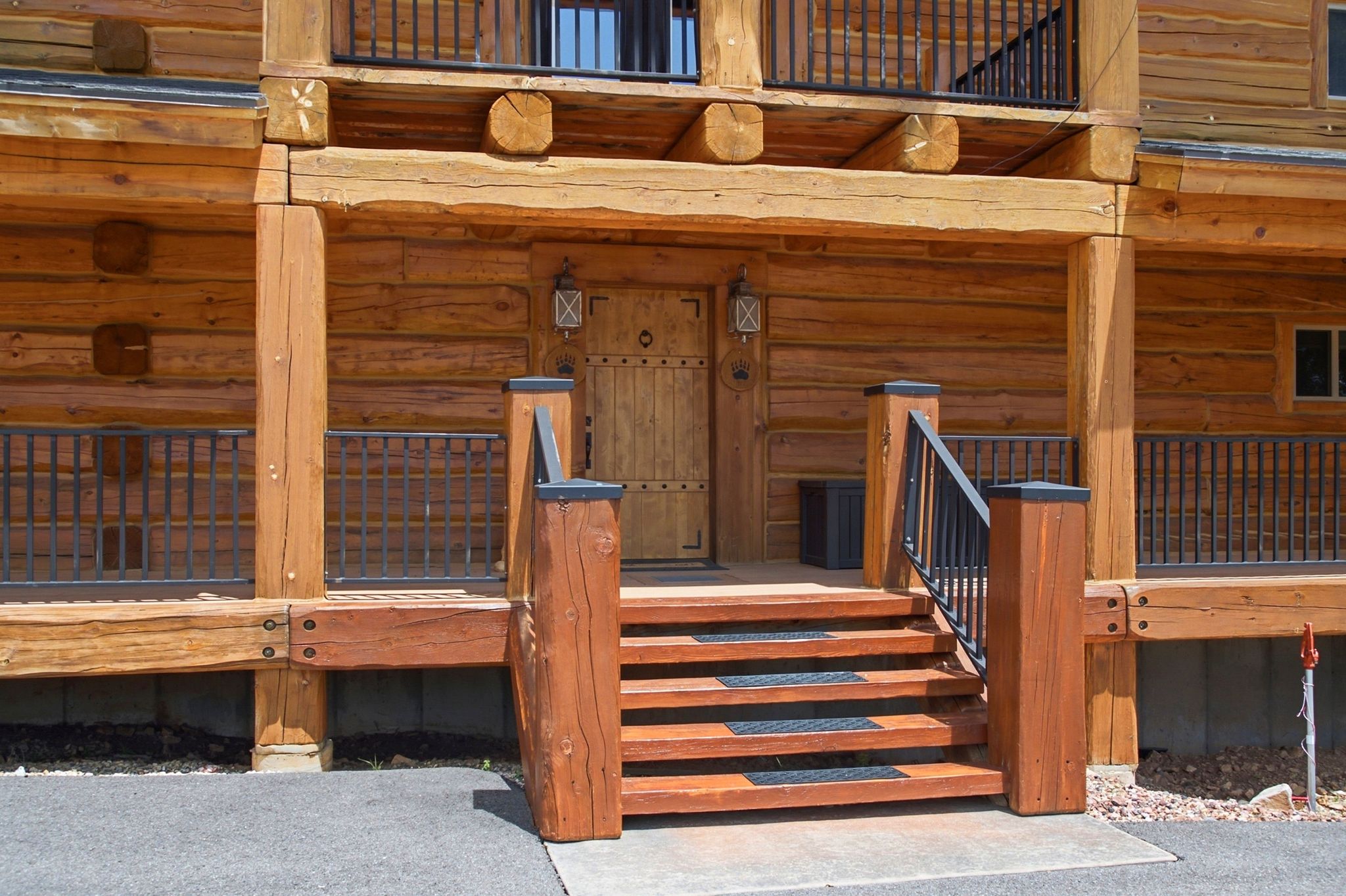 Rustic wood exterior featuring a plank-style entry door with iron hardware, a multi-tier wooden staircase, and wrought iron railings