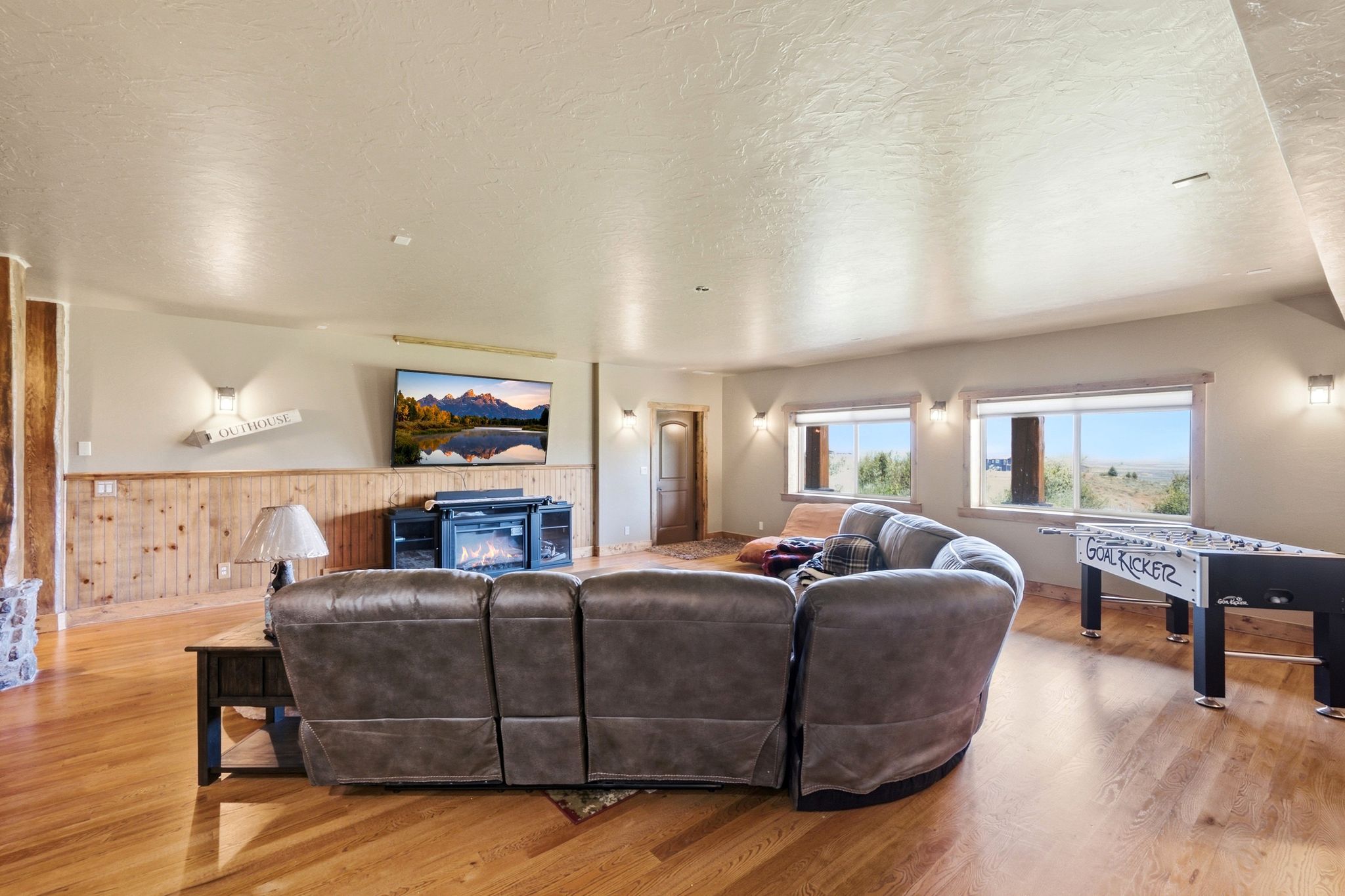 Spacious entertainment area featuring wood-finish flooring, wainscoting, and recessed lighting