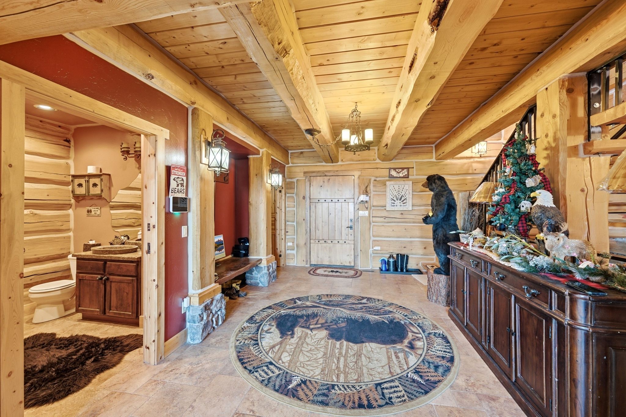 Entryway featuring exposed wood beams, log walls, ceramic tile flooring, and a solid wood entry door