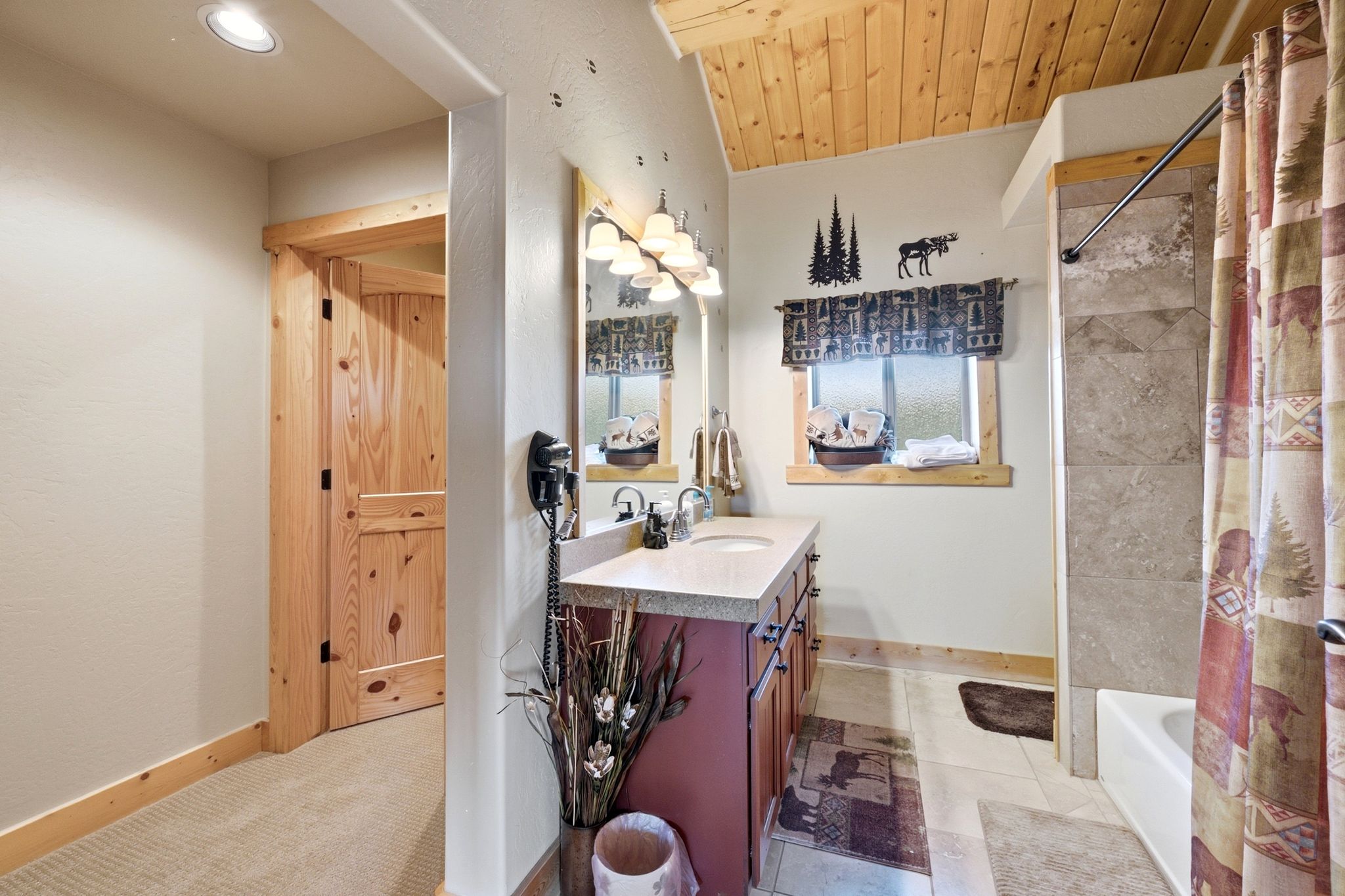 Bathroom featuring a single vanity with a solid surface countertop, an undermount sink, and wood-finish cabinetry