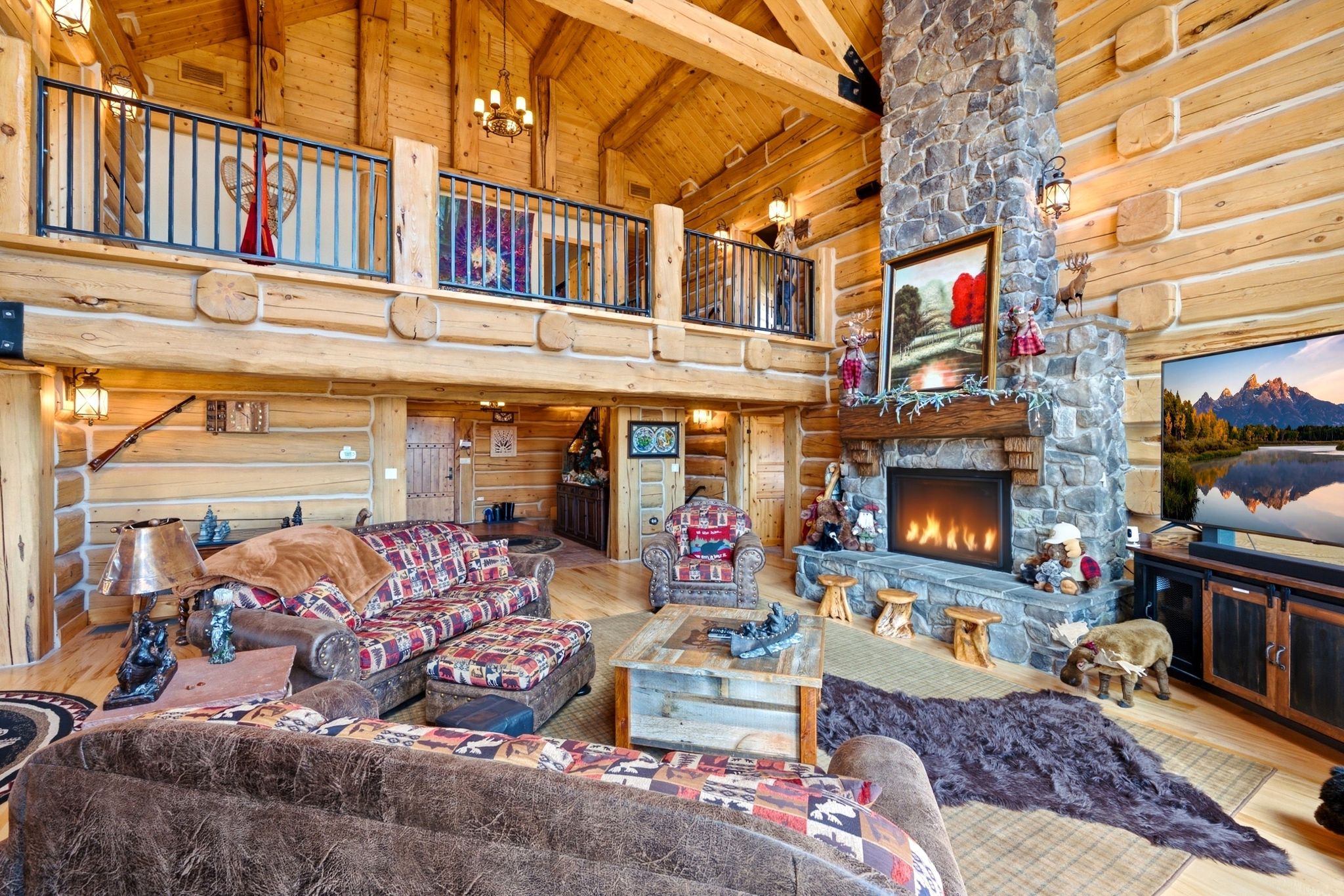 Great room featuring a floor-to-ceiling stone fireplace, open-beam vaulted ceilings, and natural log walls